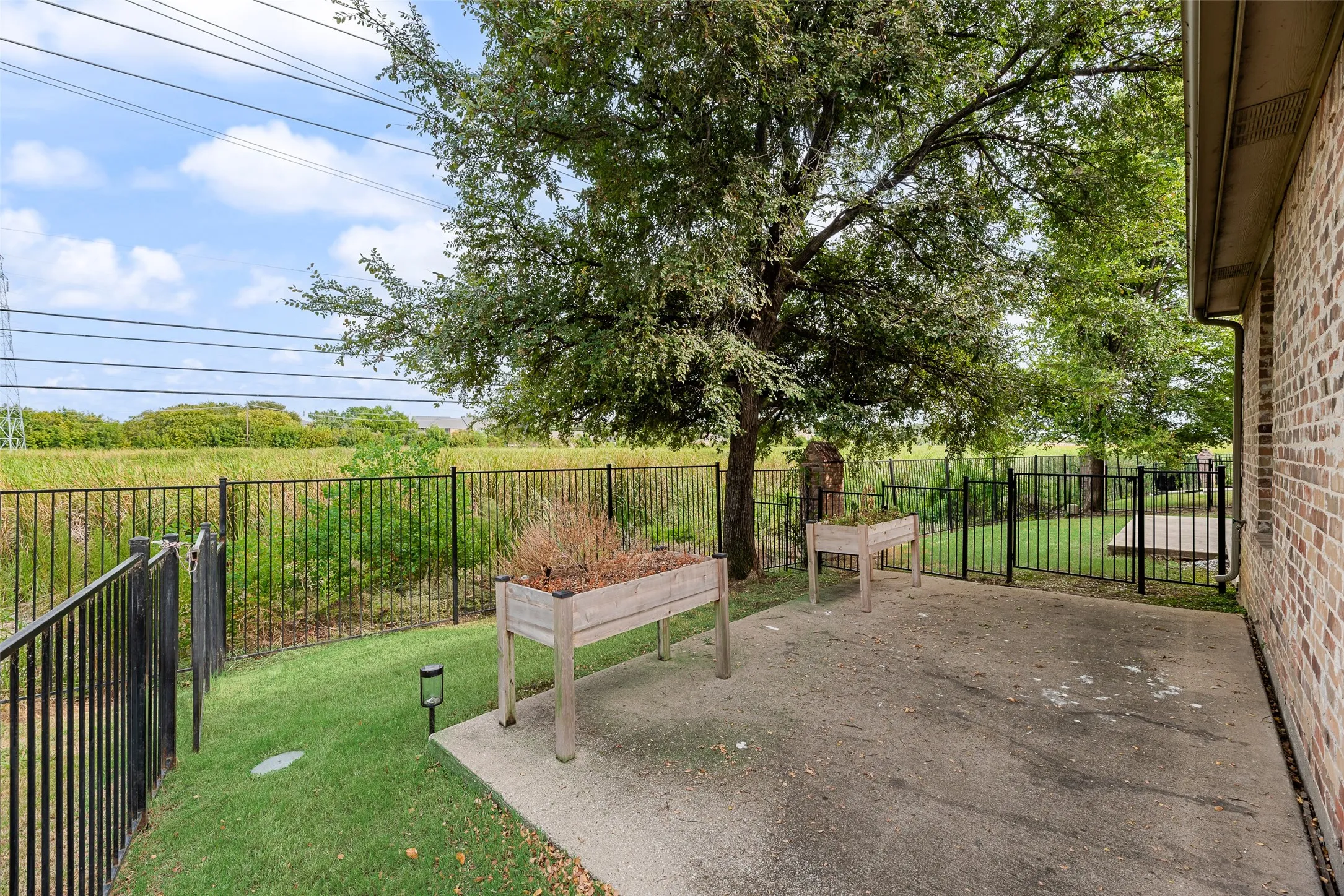 Private patio with a concrete surface, bordered by a black metal fence