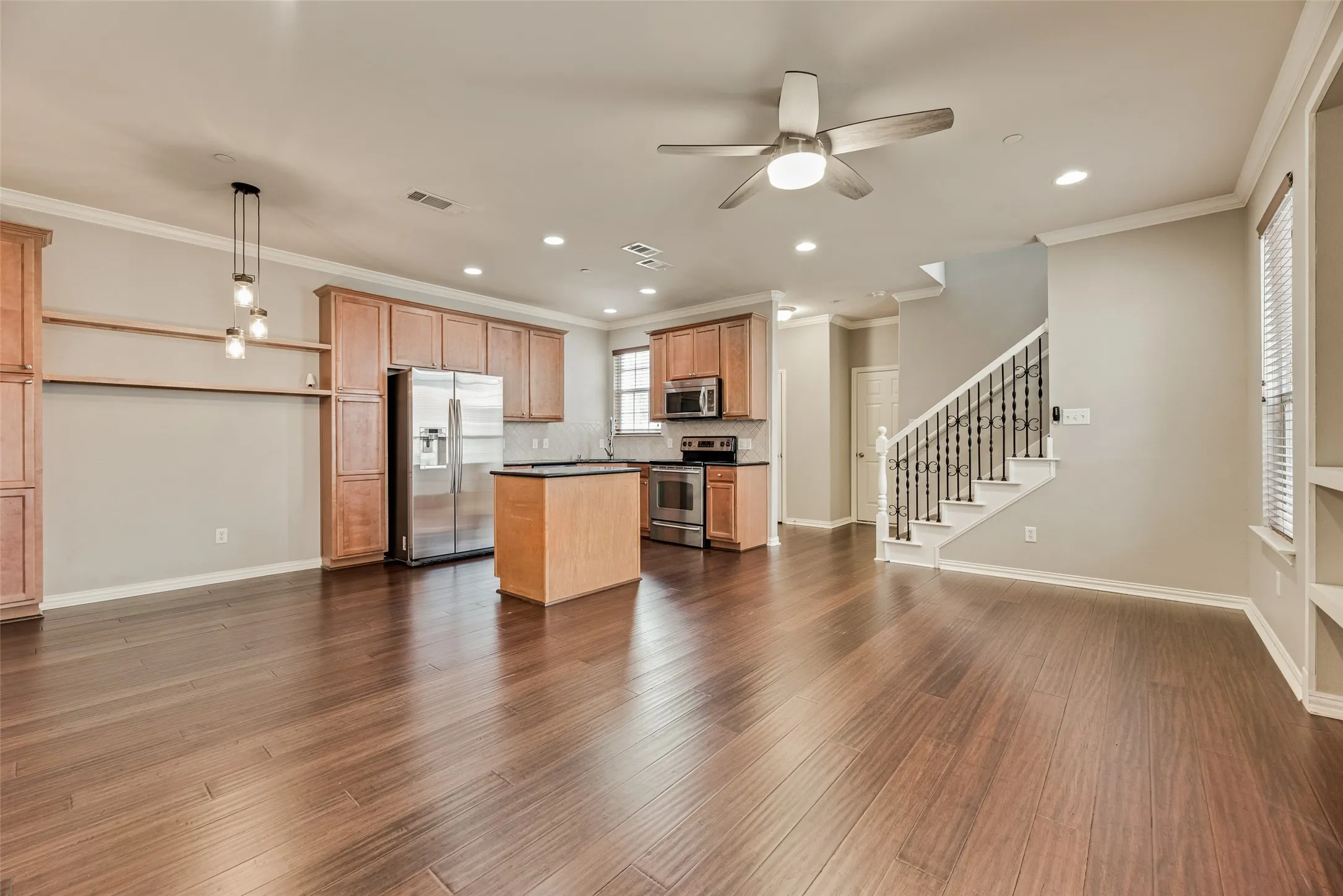 Wood-finish flooring throughout, kitchen with wood cabinetry, stainless steel appliances, and a central island
