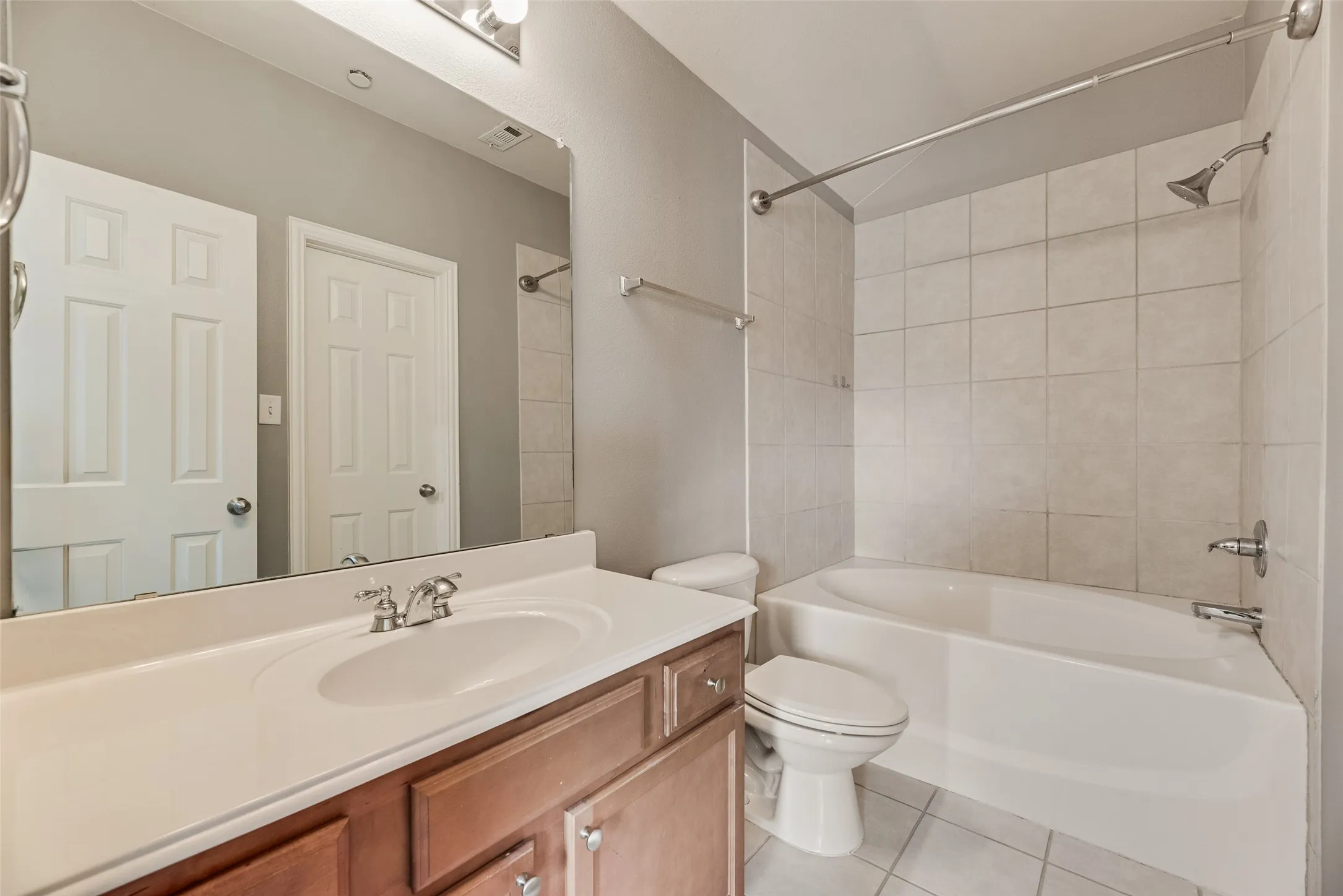 Full bathroom featuring a single vanity with wood-finish cabinetry, a white countertop, and an integrated sink
