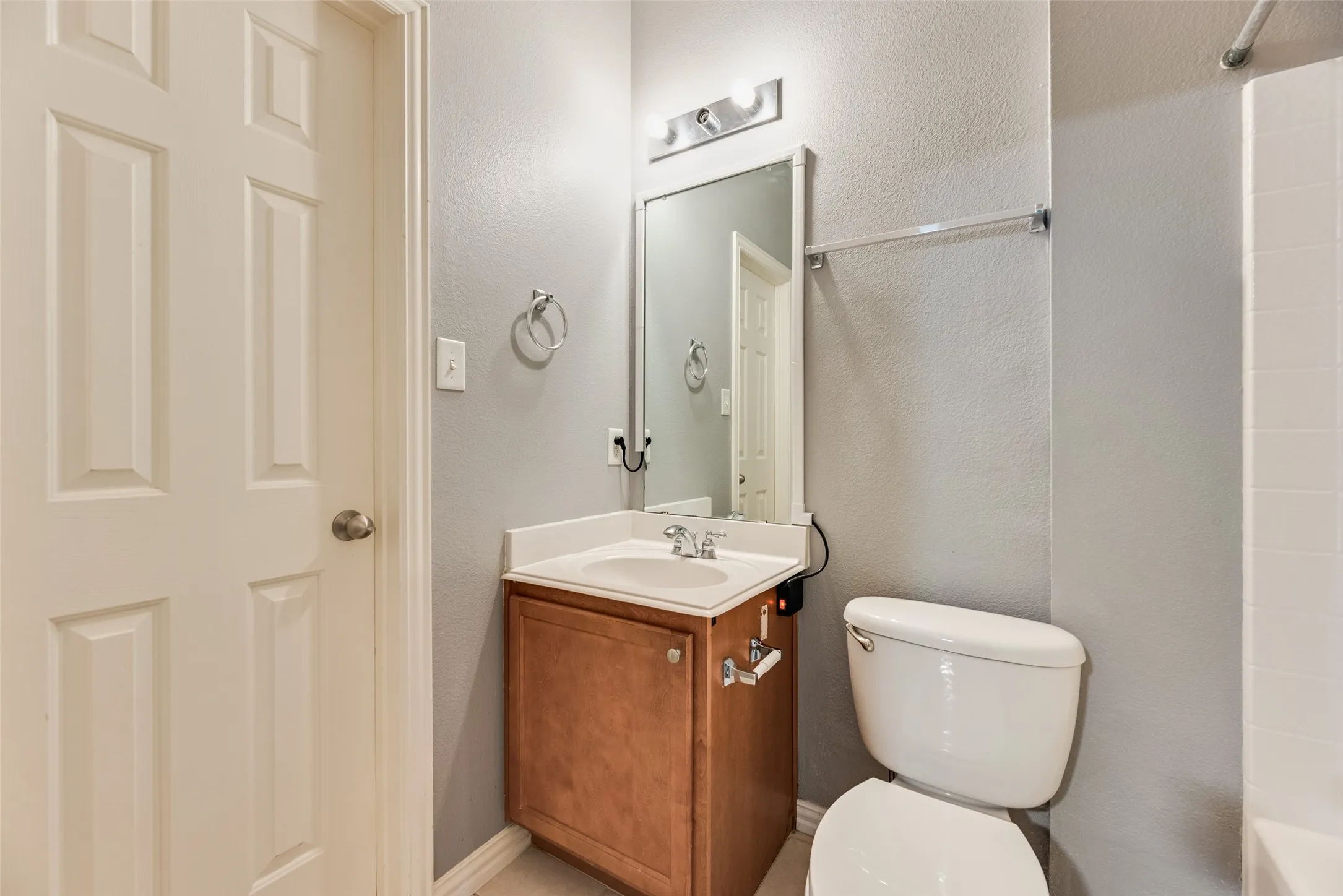 Bathroom featuring a wood-finish vanity with an integrated sink, a wall-mounted mirror, and a toilet