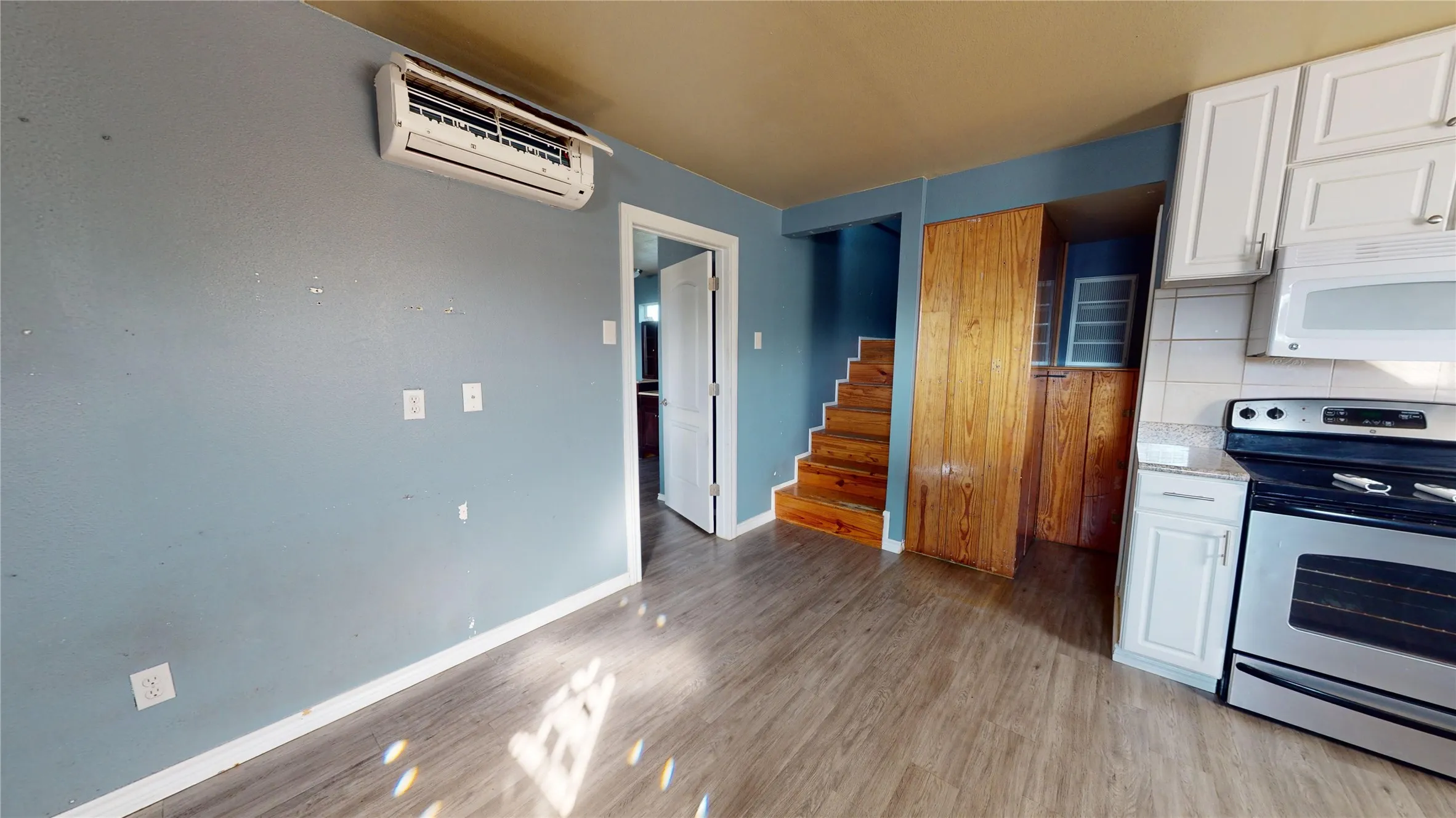 Wood-finish flooring, white cabinetry with silver hardware, stainless steel range, and a built-in microwave