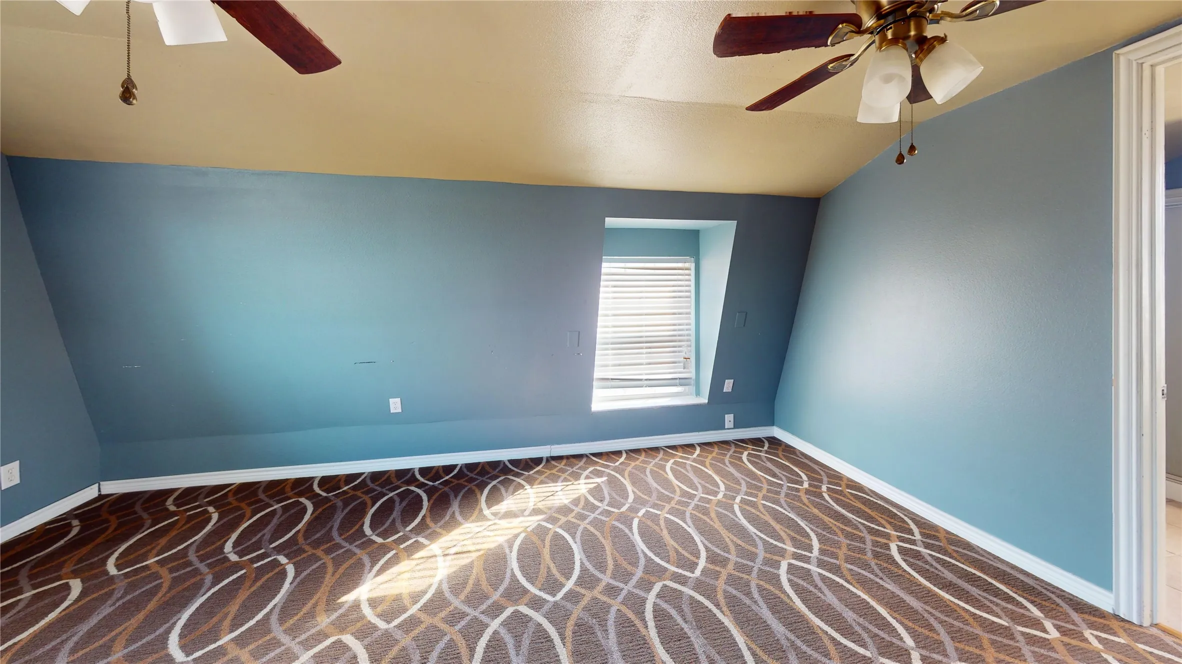 Room featuring patterned carpeting, sloped ceilings, and a built-in window with horizontal blinds