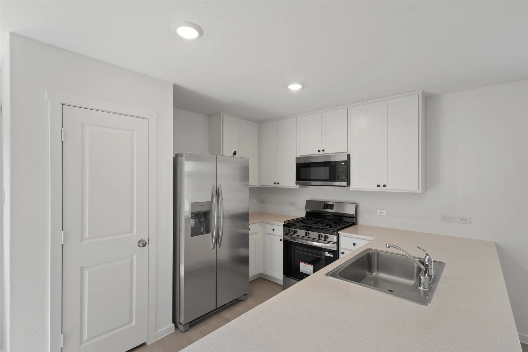 Kitchen featuring white cabinetry, stainless steel appliances, recessed lighting, and light-toned countertops