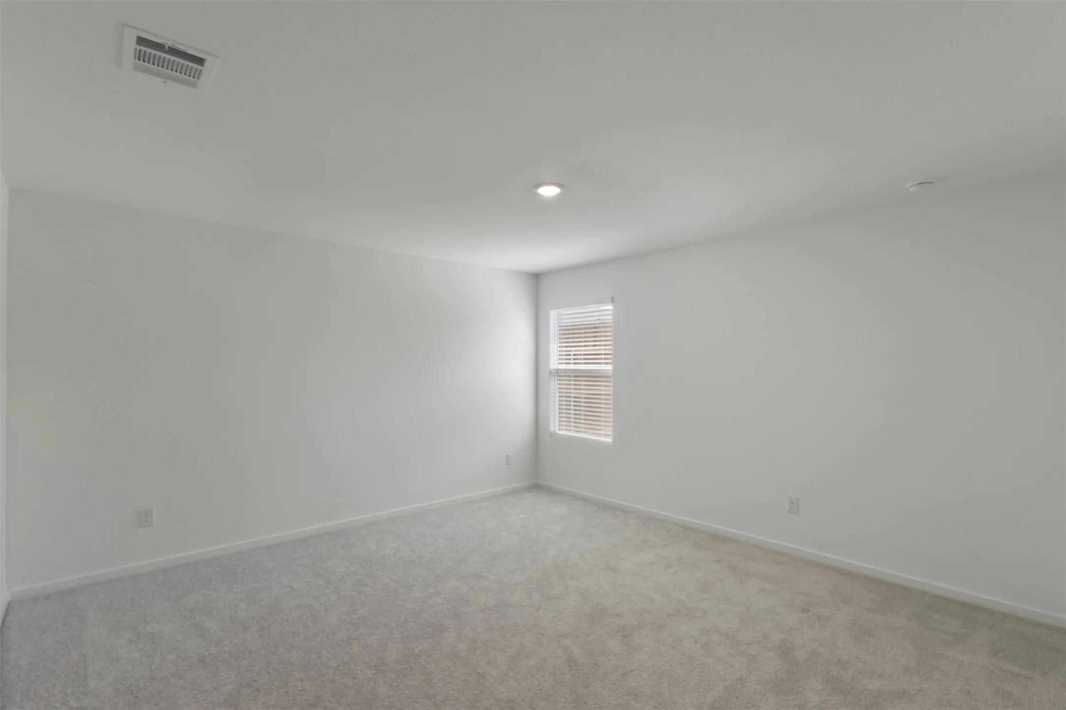 Neutral interior walls, recessed ceiling lighting, light-colored carpet, window with blinds, and white trim
