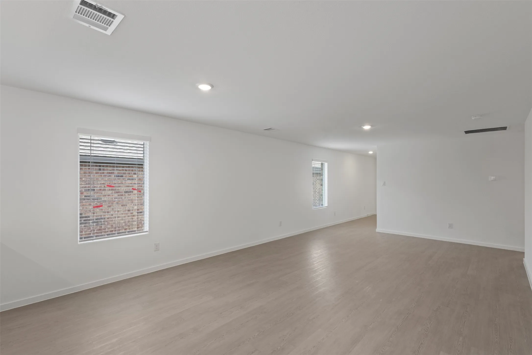 Recessed lighting, light wood-finish flooring, and white walls
