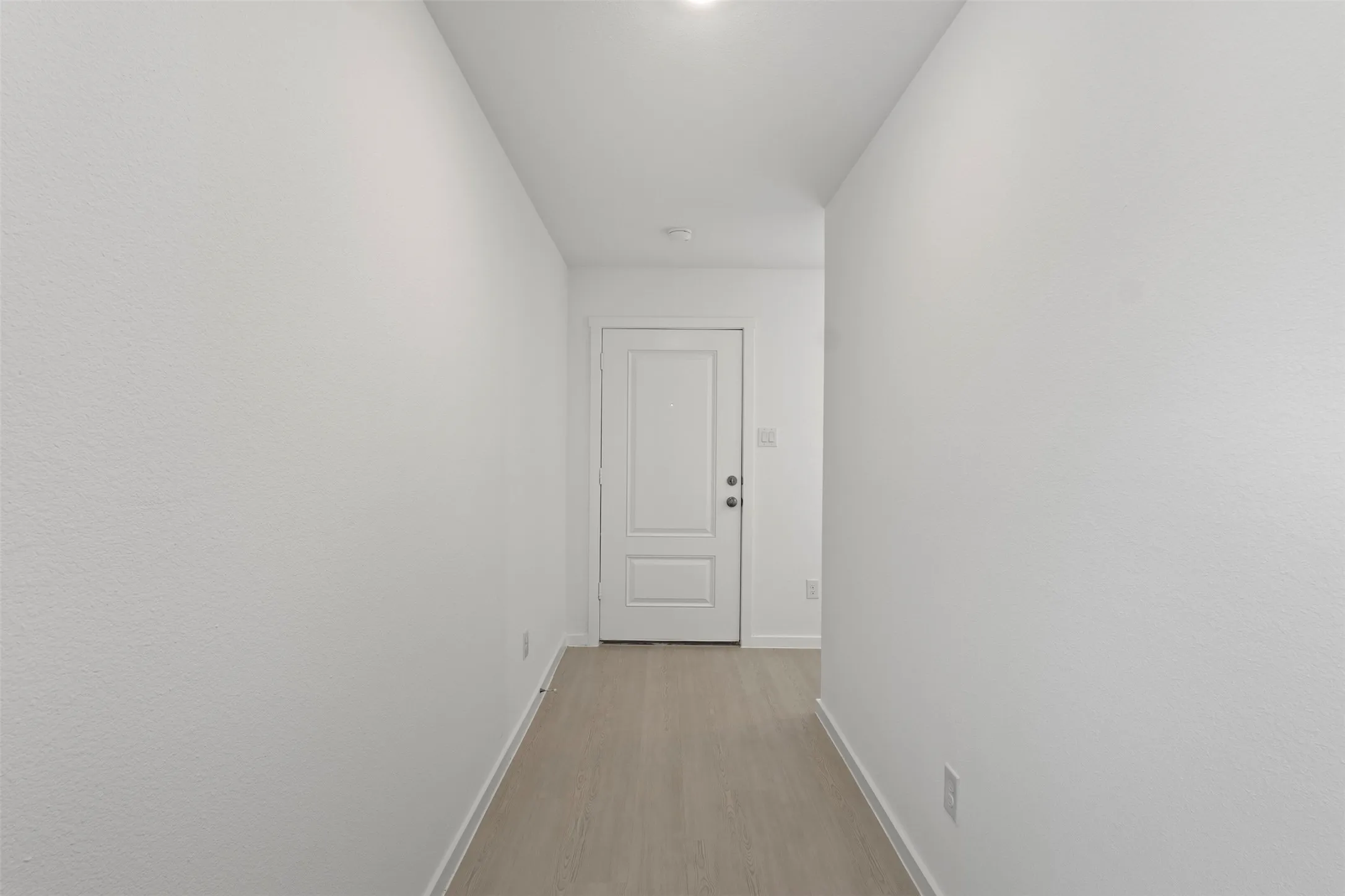 Hallway featuring light wood-finish flooring, white walls, and a recessed ceiling light