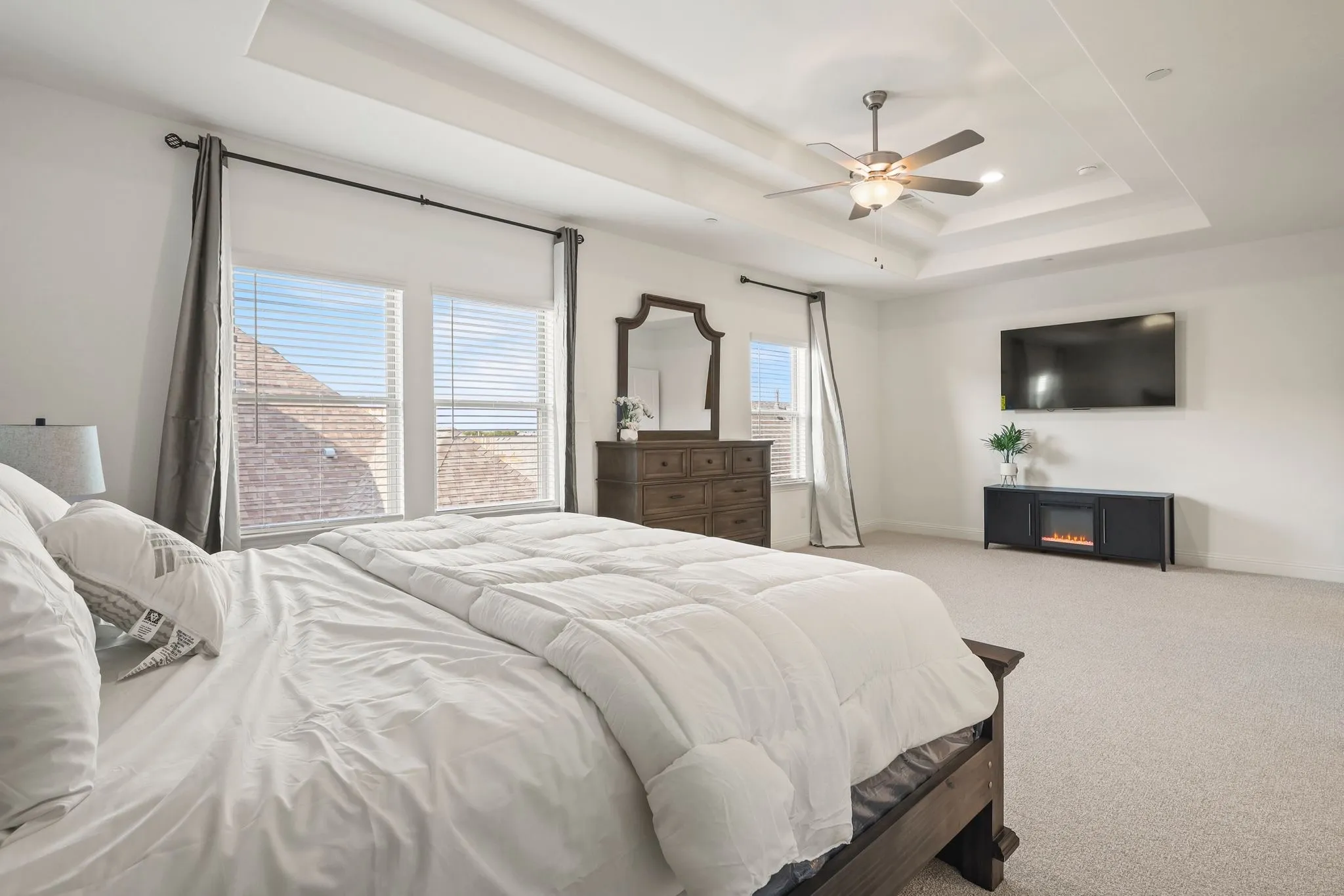 Carpeted bedroom featuring ceiling fan and a tray ceiling