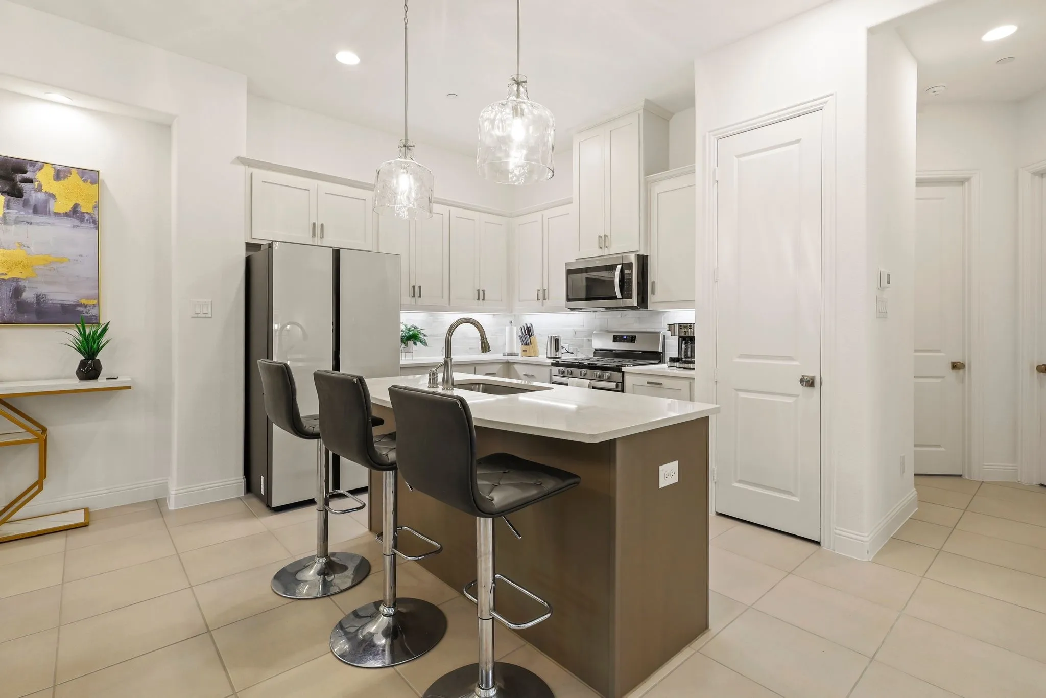 Kitchen with white cabinets, sink, stainless steel appliances, and a center island with sink