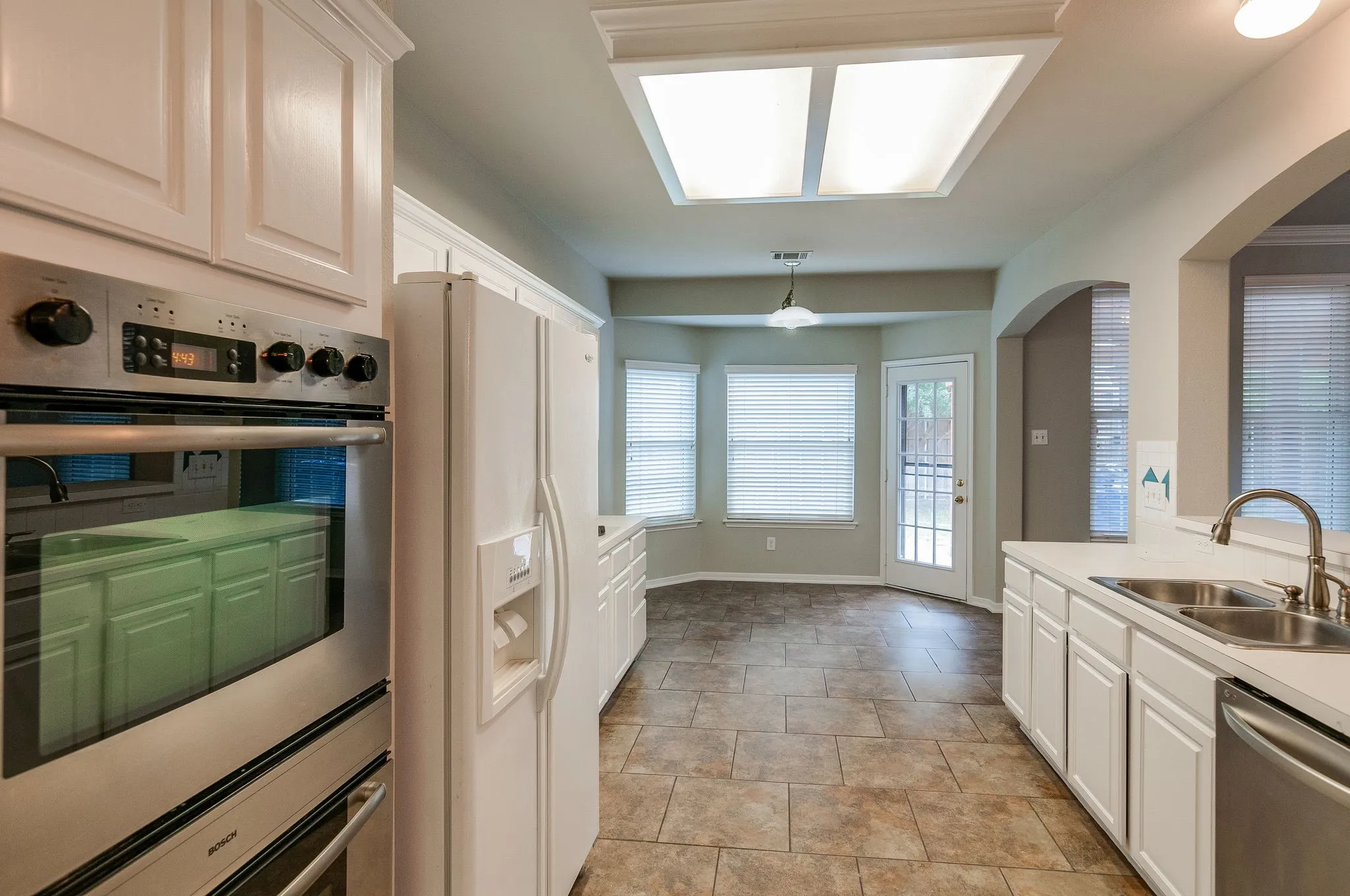 Kitchen featuring white cabinetry, stainless steel wall oven, and tile flooring