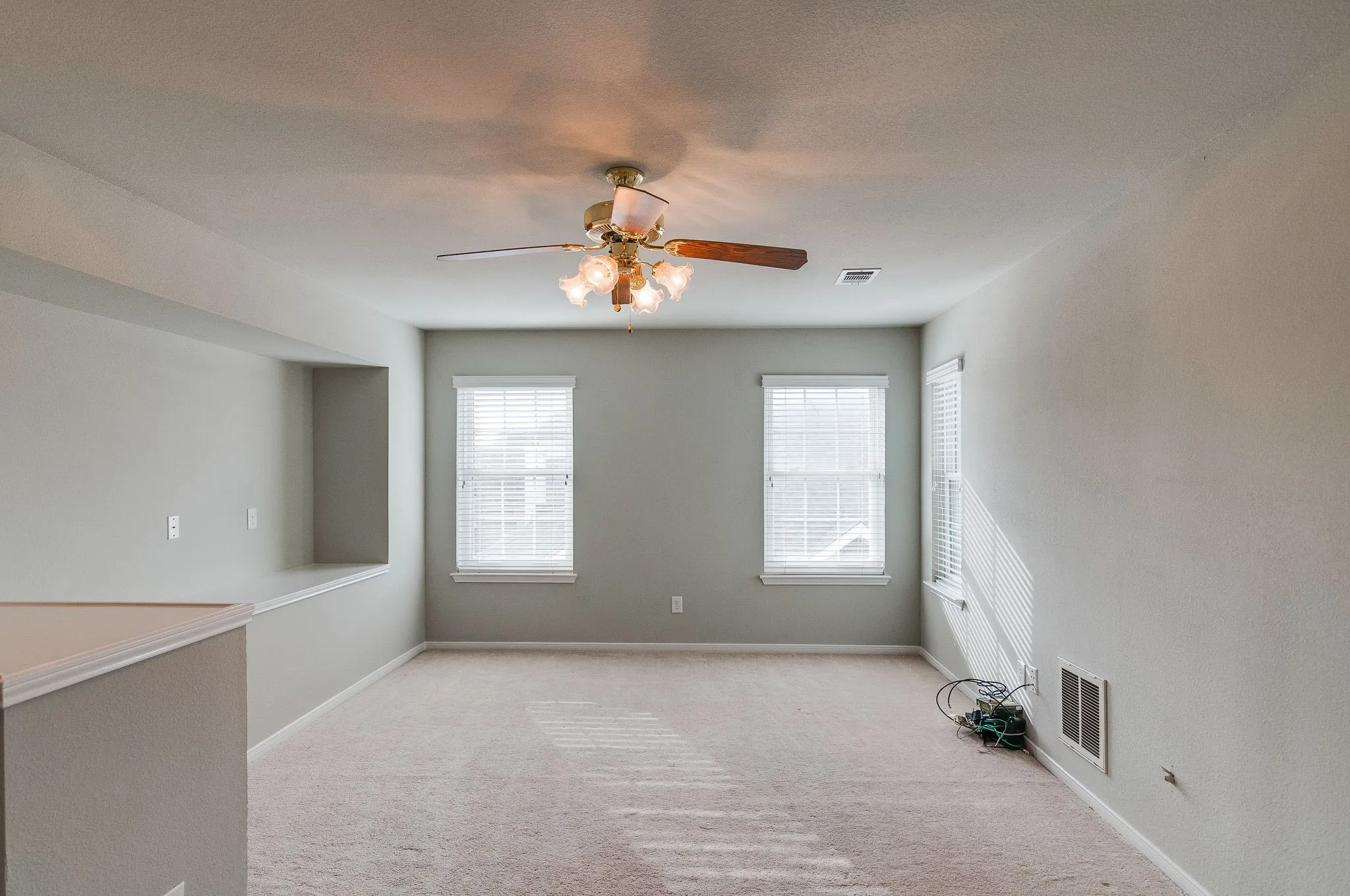 Recessed wall niche with a built-in shelf, multiple windows with blinds, and a ceiling fan with integrated lighting
