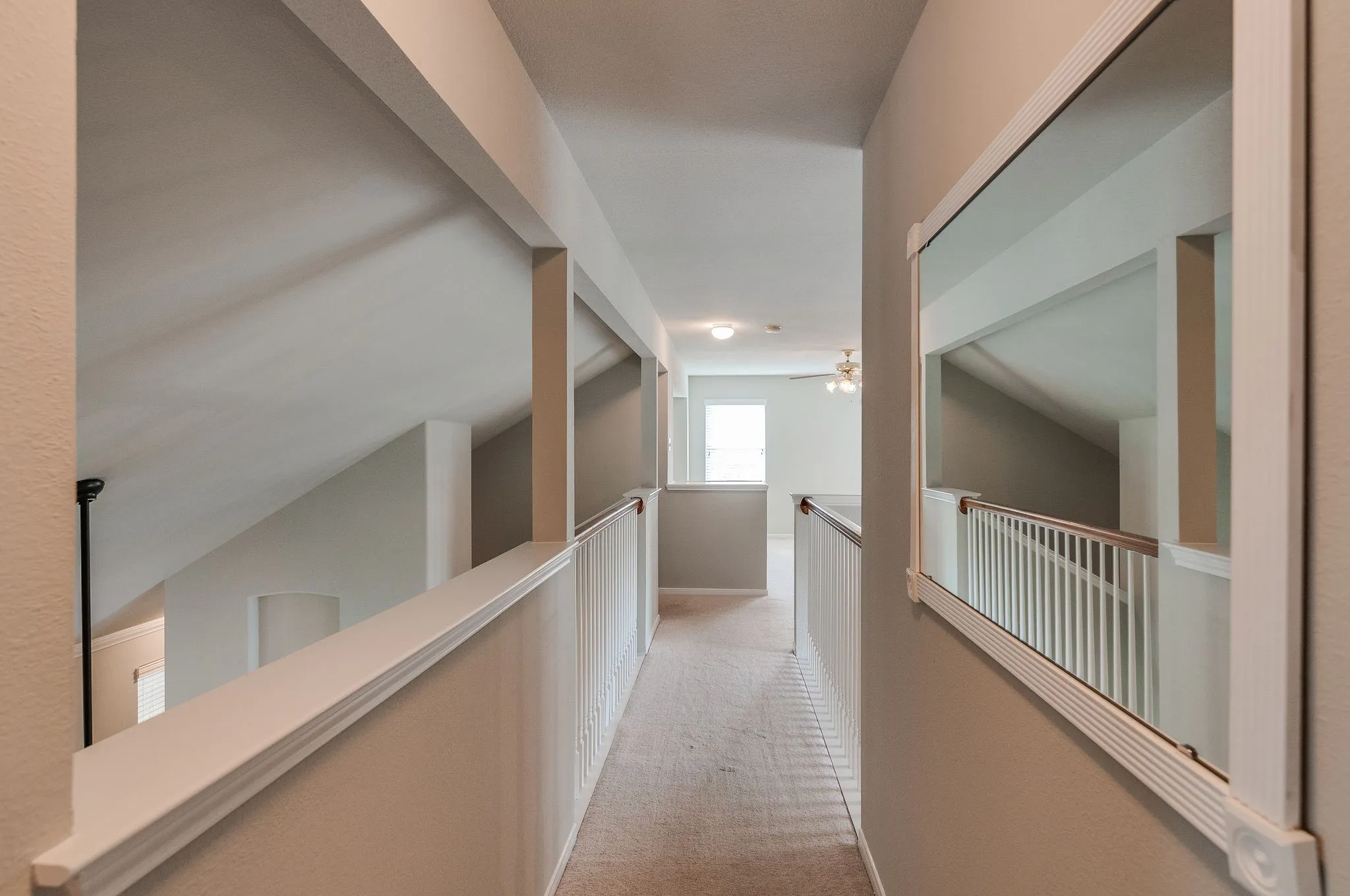 Upper-level hallway with carpet flooring, white trim, and a white framed mirror