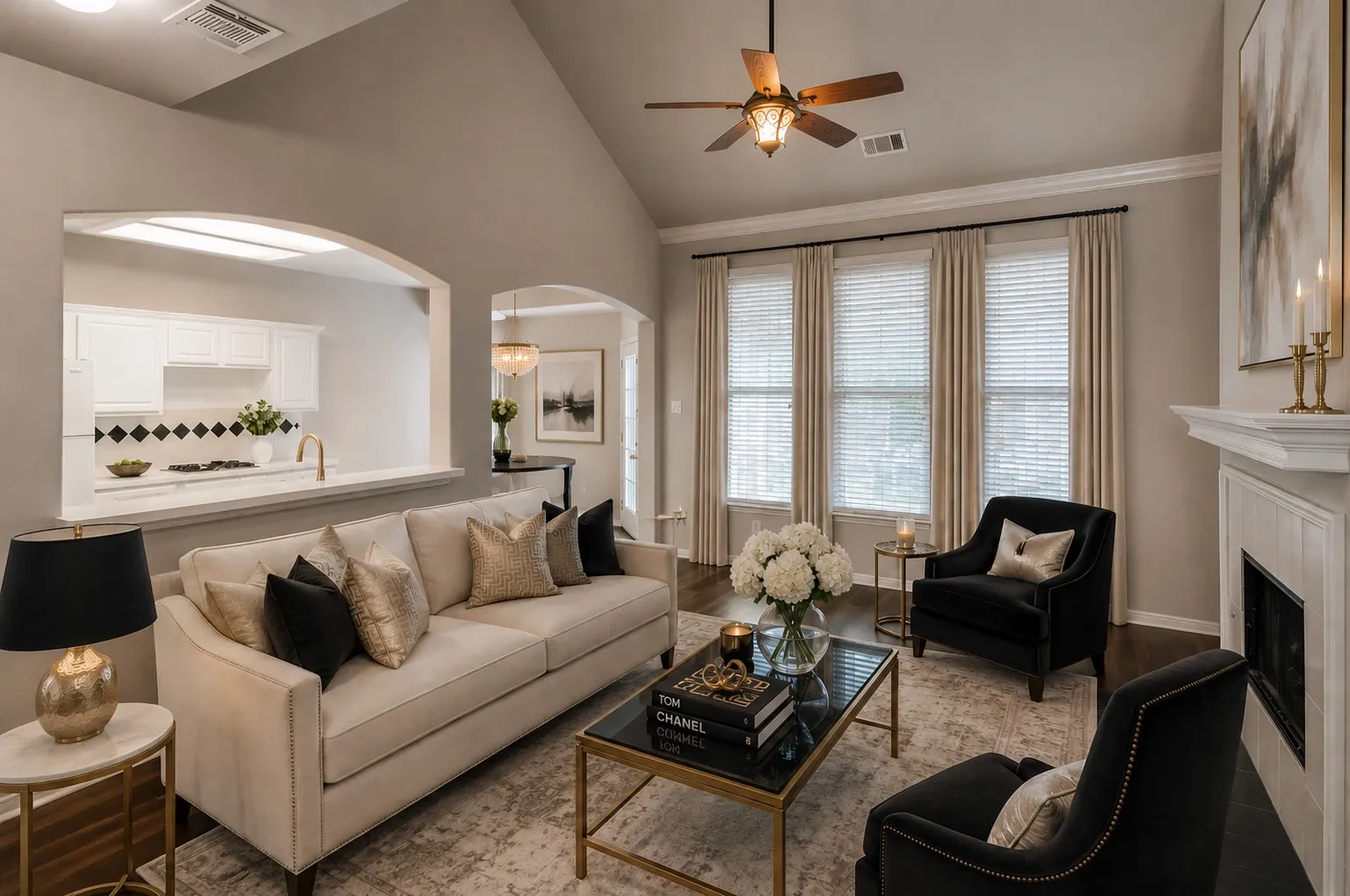 Vaulted ceiling with a ceiling fan, three vertical windows, a white mantel, and dark wood-finish flooring