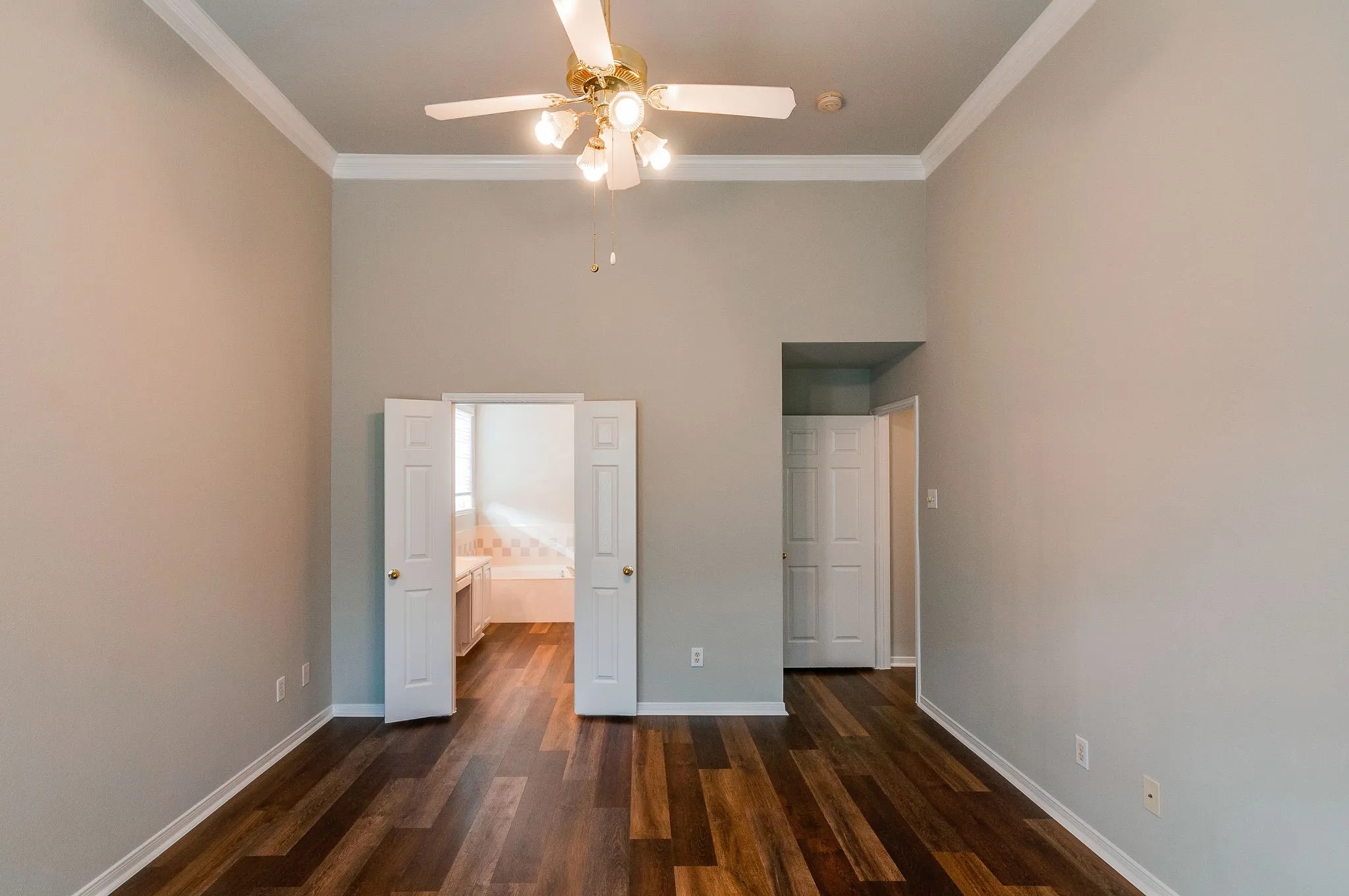 Wood-finish flooring with crown molding and a ceiling fan