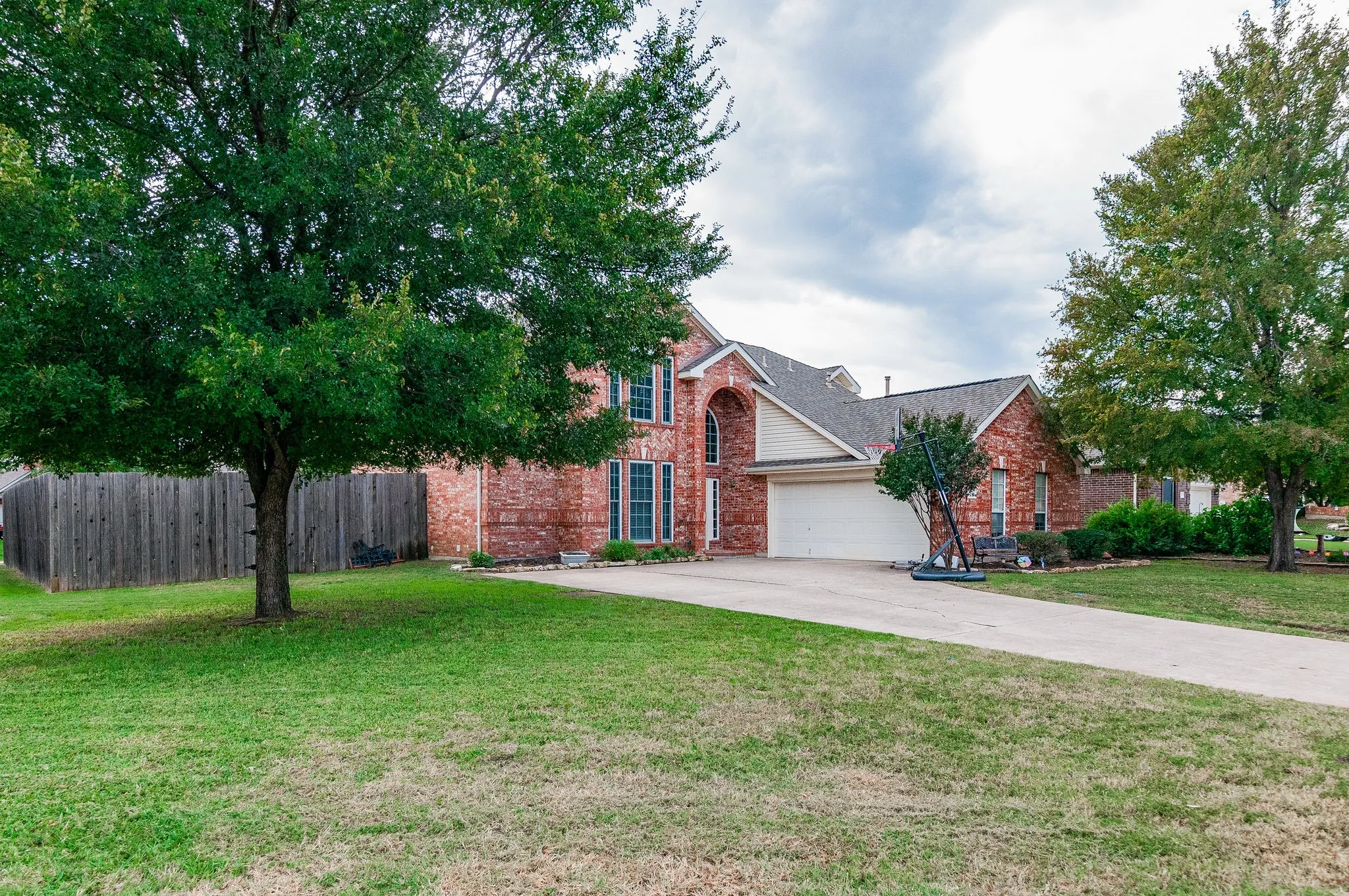 Two-story brick exterior with an arched entryway, two-car garage, and a concrete driveway