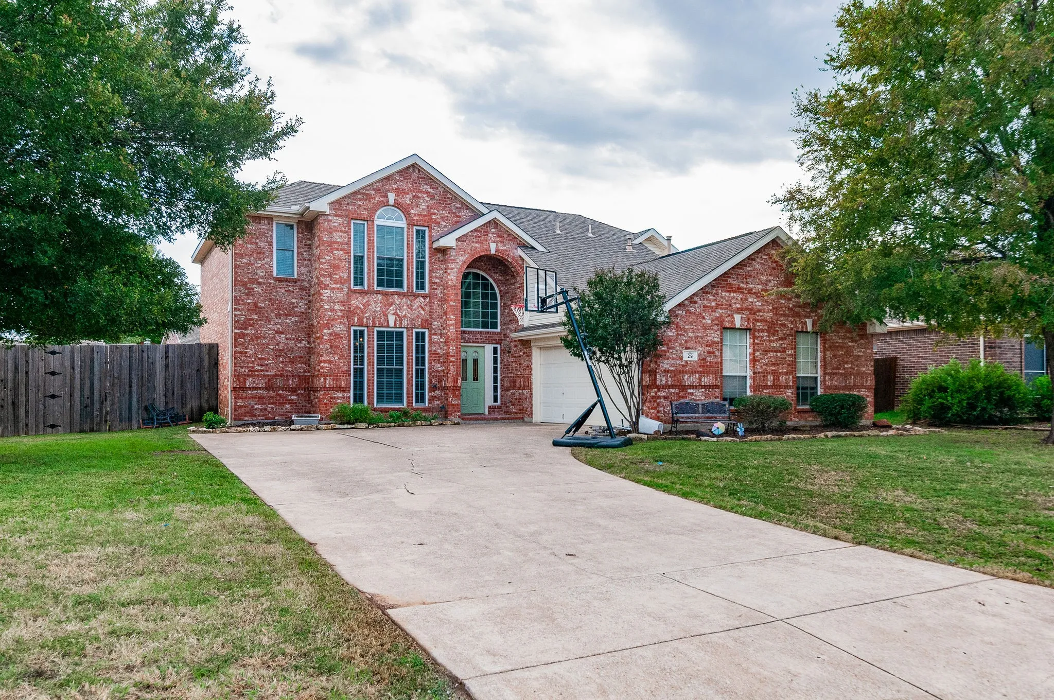 Brick exterior with a light green front door, arched window details, and a concrete driveway