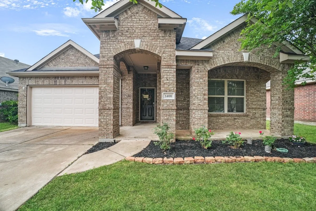 Brick exterior with arched entryway, single-panel garage door, and a landscaped front yard with brick edging