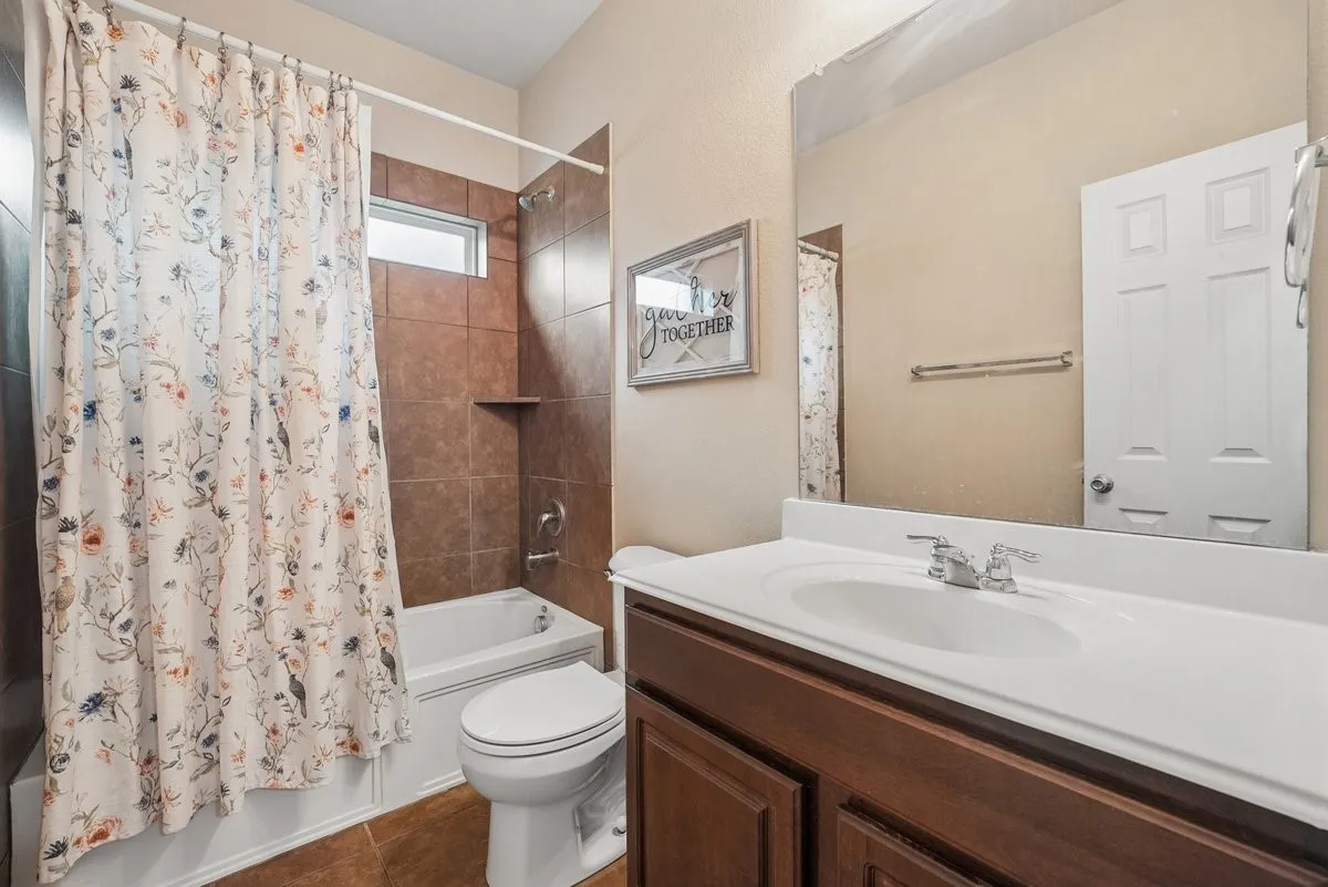 Bathroom featuring a built-in bathtub, tile surround, vanity with an integrated sink, and a large wall-mounted mirror
