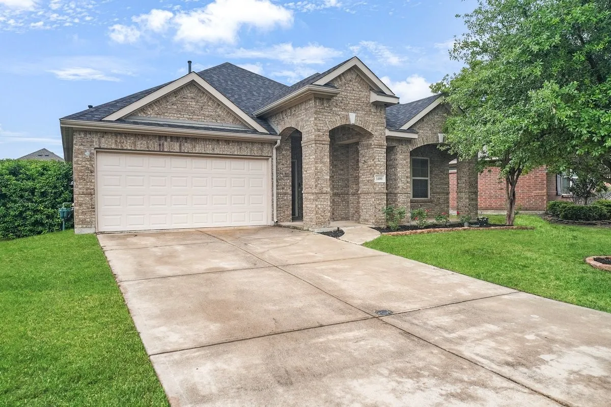 Brick exterior with arched entryways, dark shingle roof, and an attached two-car garage