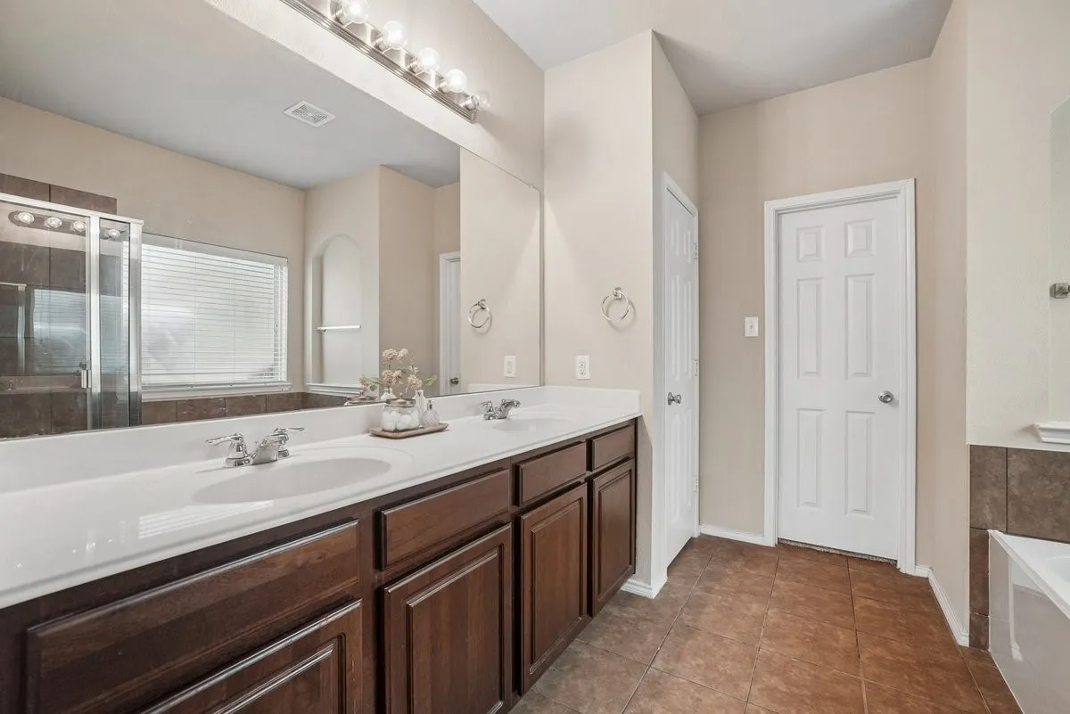 Dual vanity with integrated sinks, dark wood cabinetry, and a large mirror