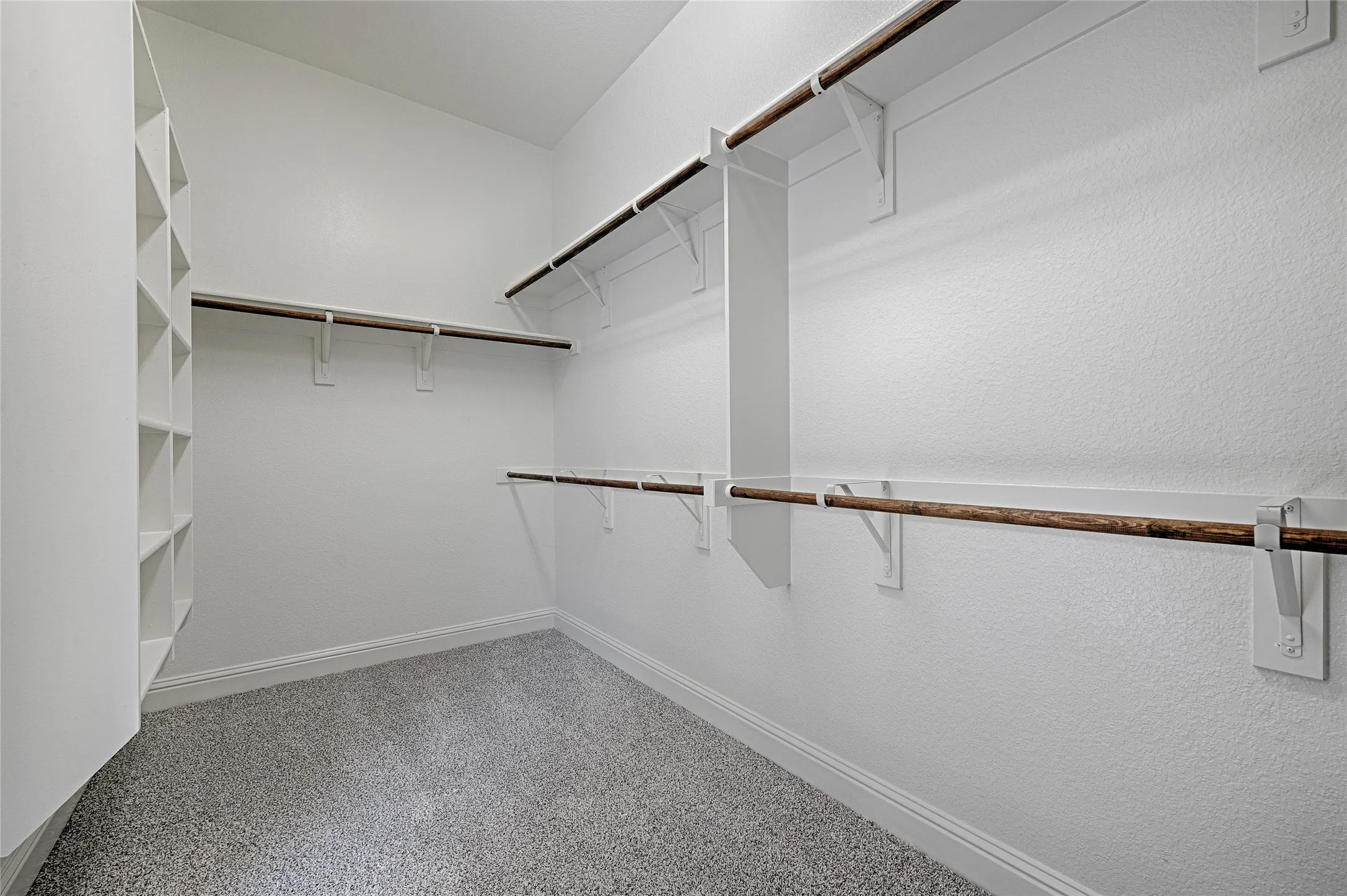 Spacious closet featuring built-in shelving, multiple hanging rods, and light-colored carpeting