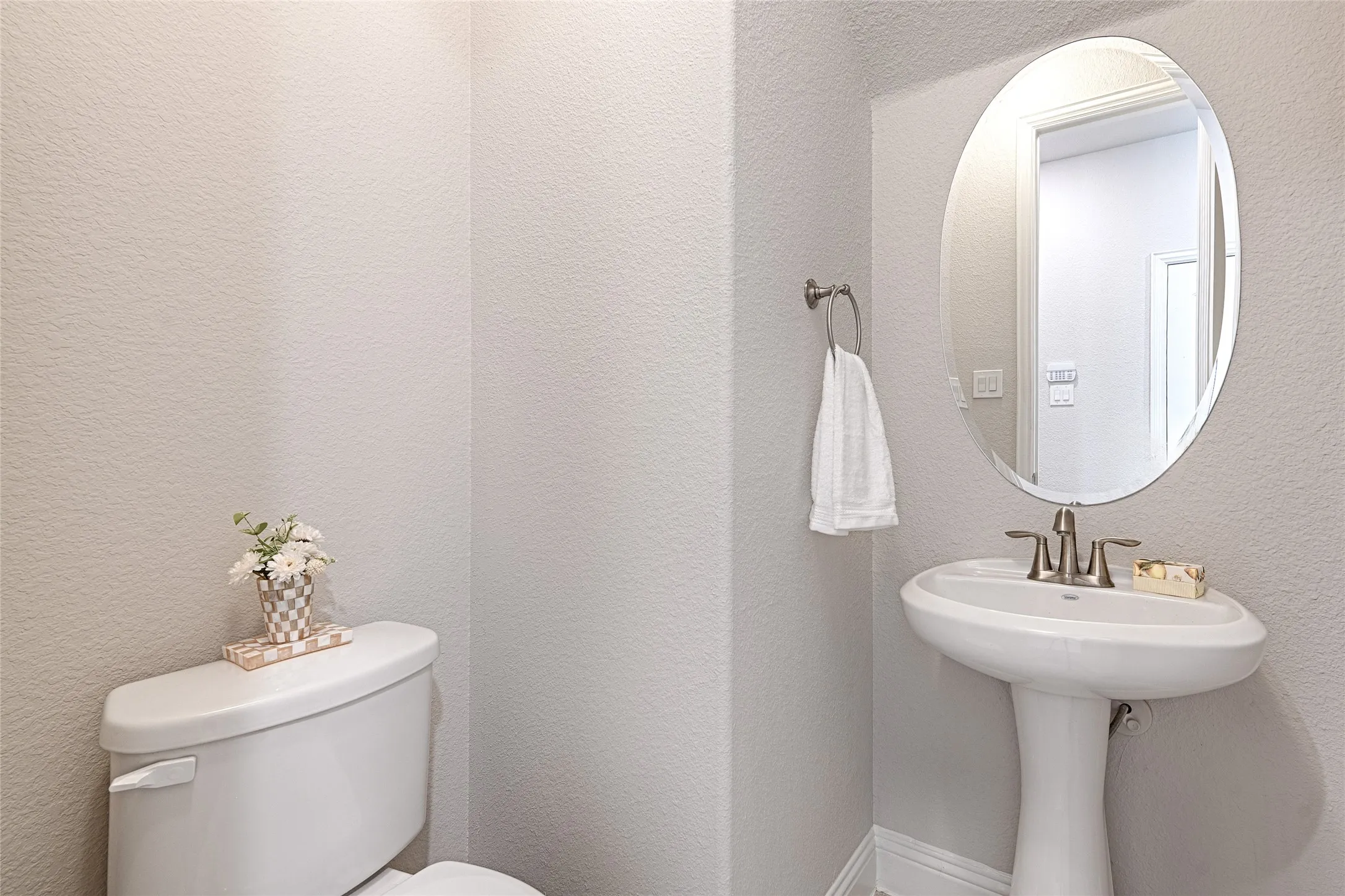 Half bath with Pedestal sink with brushed nickel faucet, oval framed mirror, and toilet
