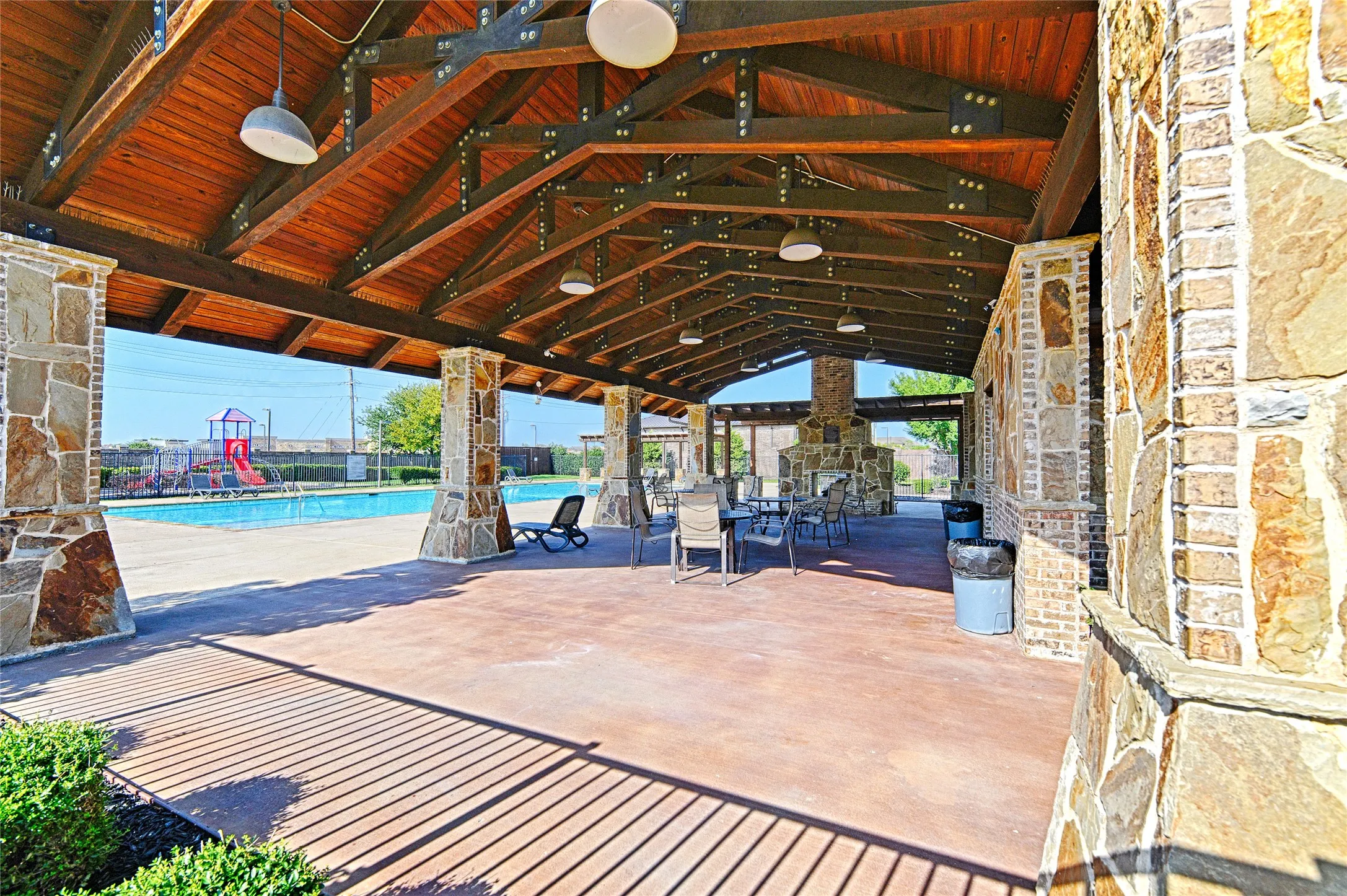 Community Lounge area. Expansive covered patio featuring a wood-plank ceiling, exposed beam structure, and stone-clad columns