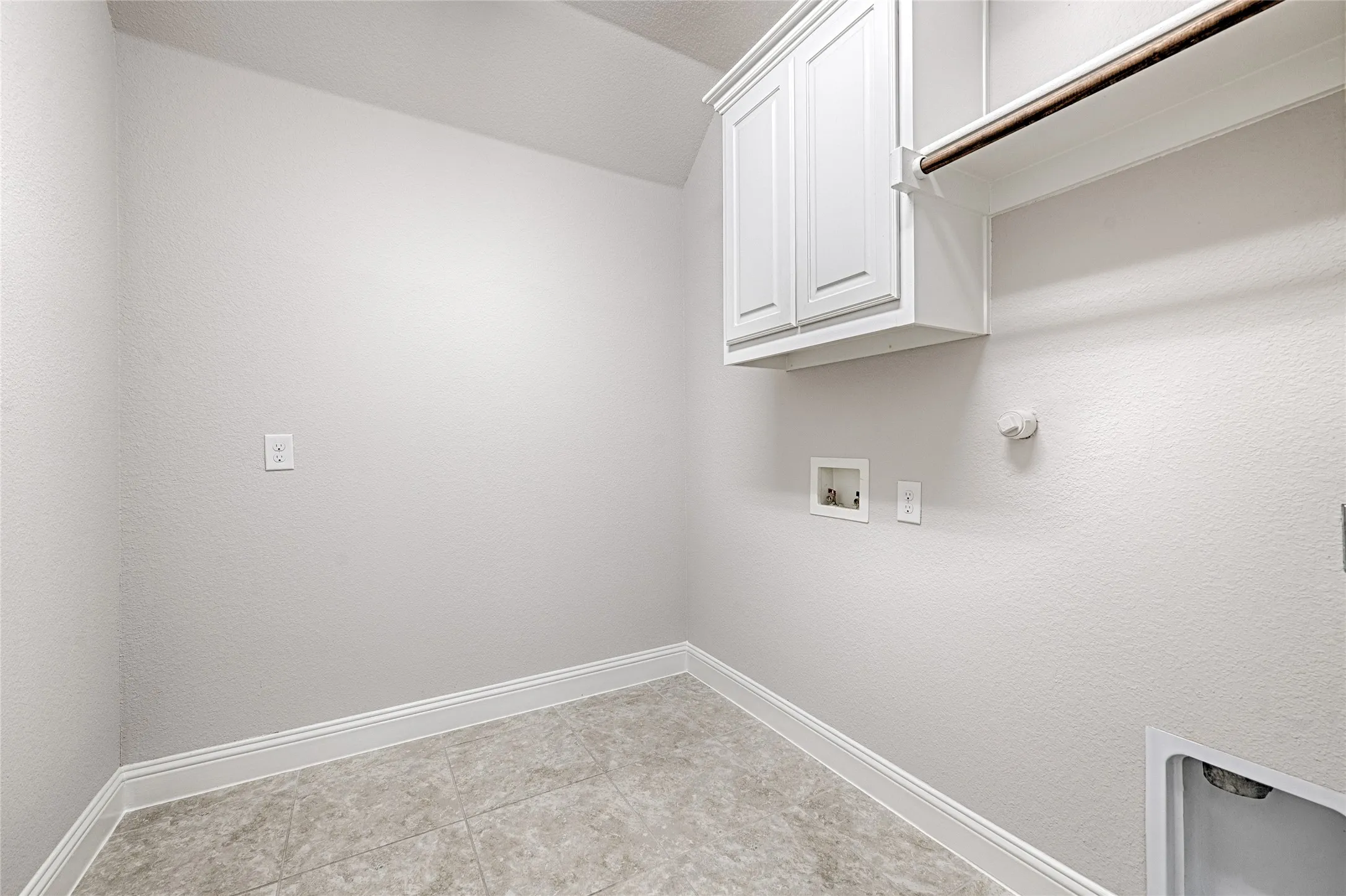 Recessed wall box for dryer hookup, overhead cabinetry, integrated clothes rod, and tile flooring