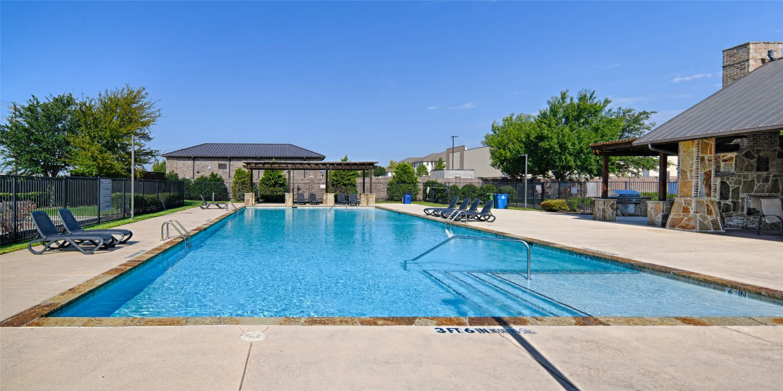 Community Rectangular swimming pool with integrated steps, surrounded by concrete decking