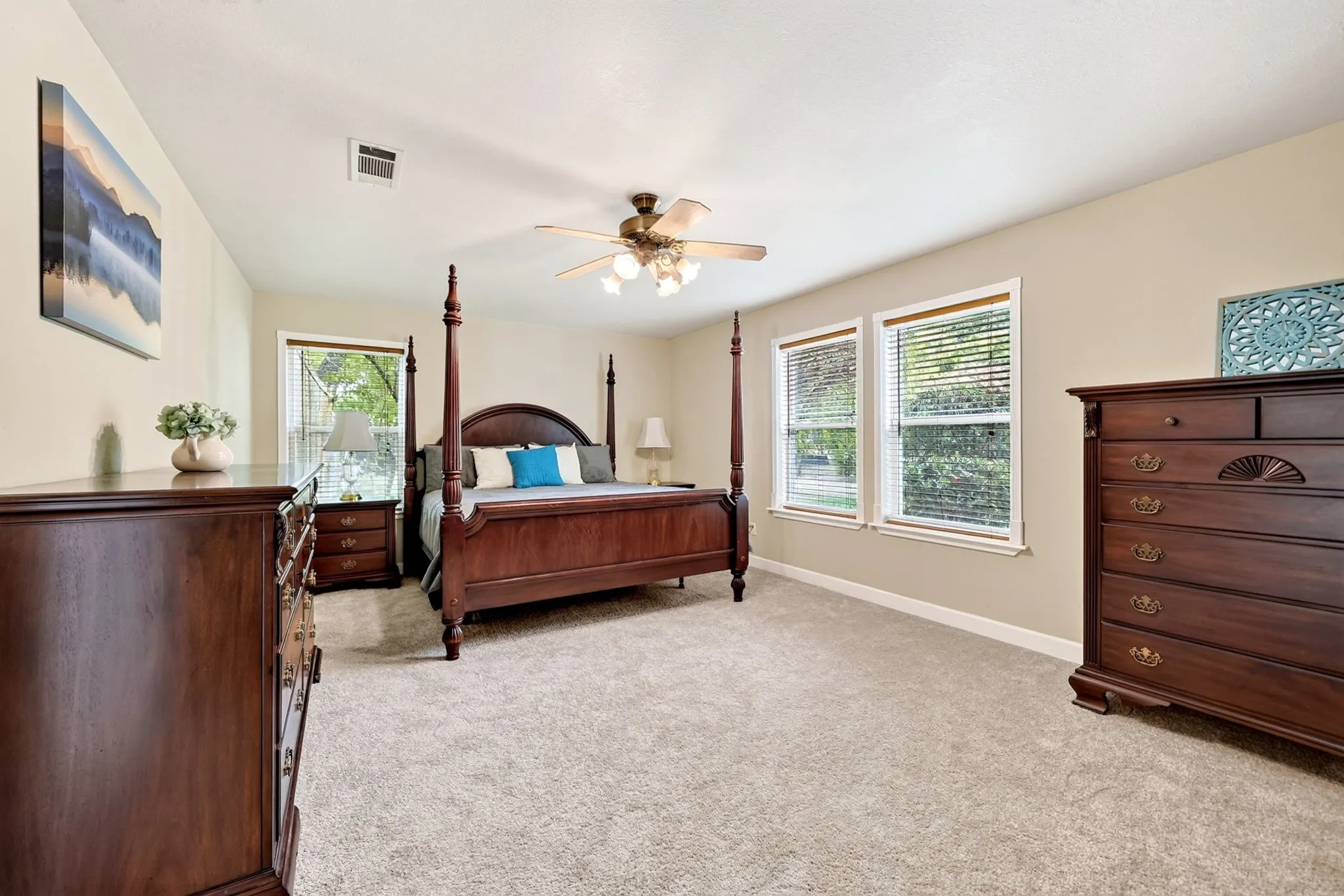 Soft carpet flooring, neutral paint tones, multiple windows, and a ceiling fan with integrated lighting
