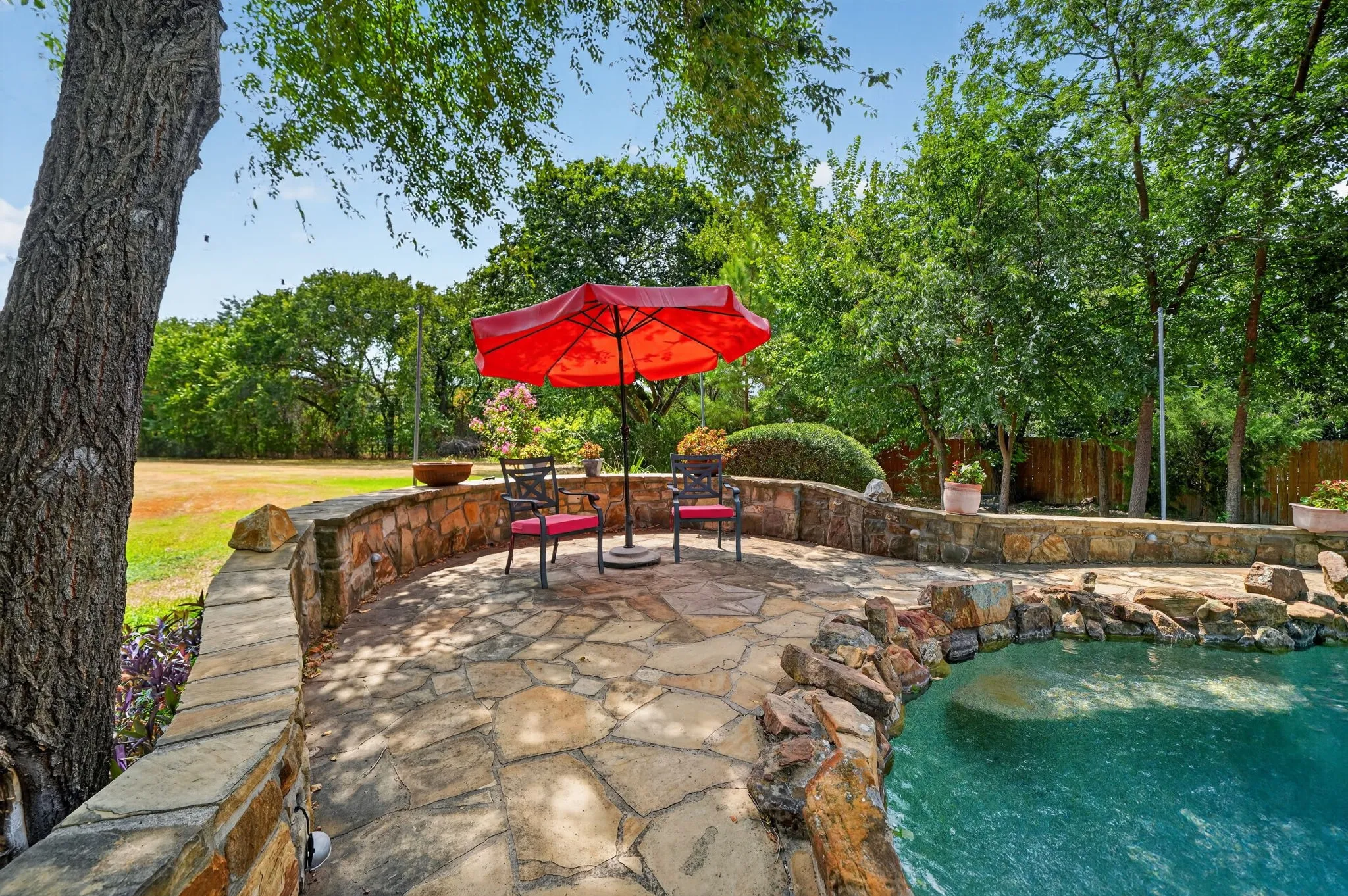 Flagstone patio with a stone retaining wall, bordering a swimming pool