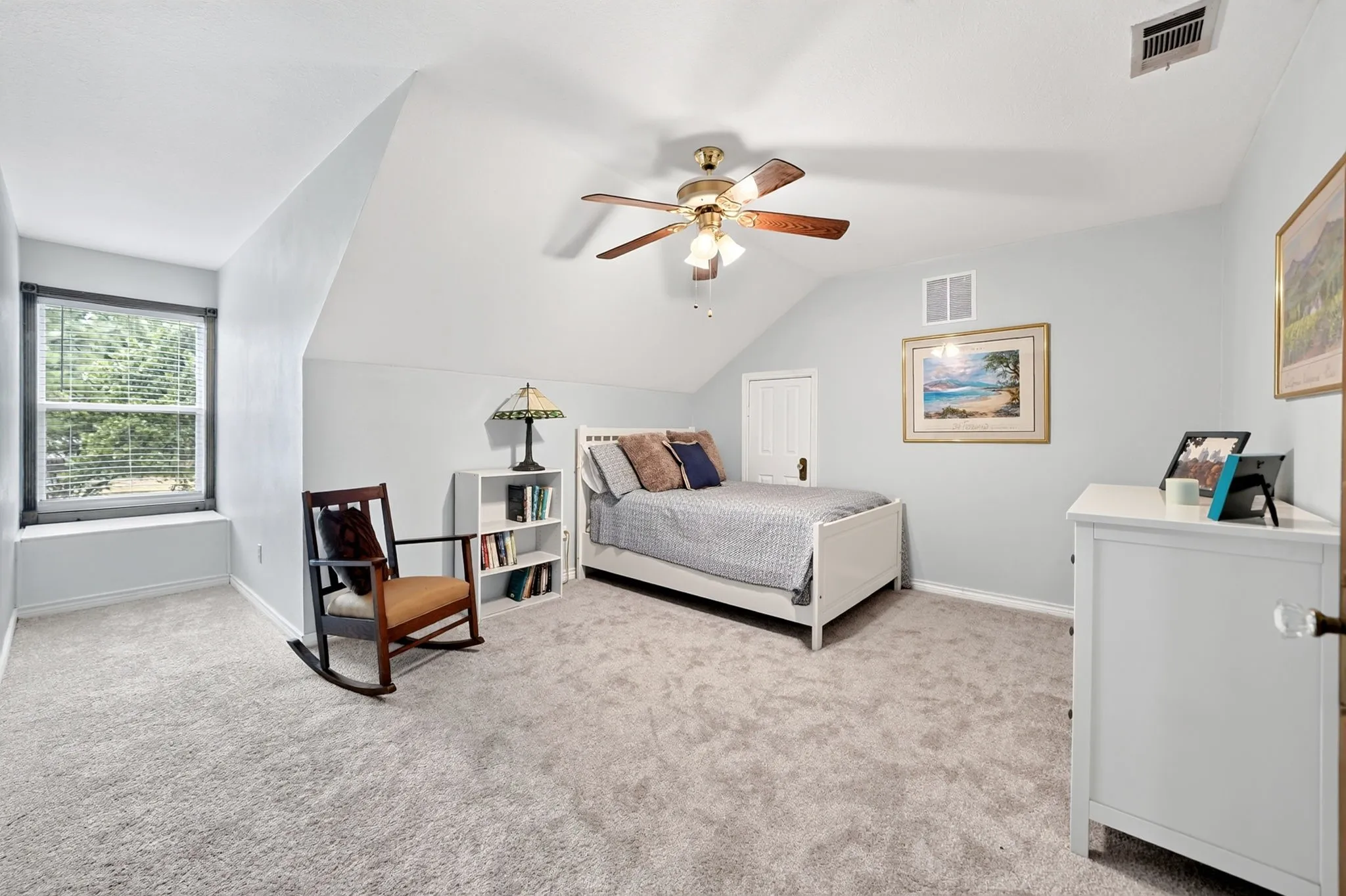 Sloped ceiling room featuring carpet flooring, a window with integrated blinds, and a ceiling fan