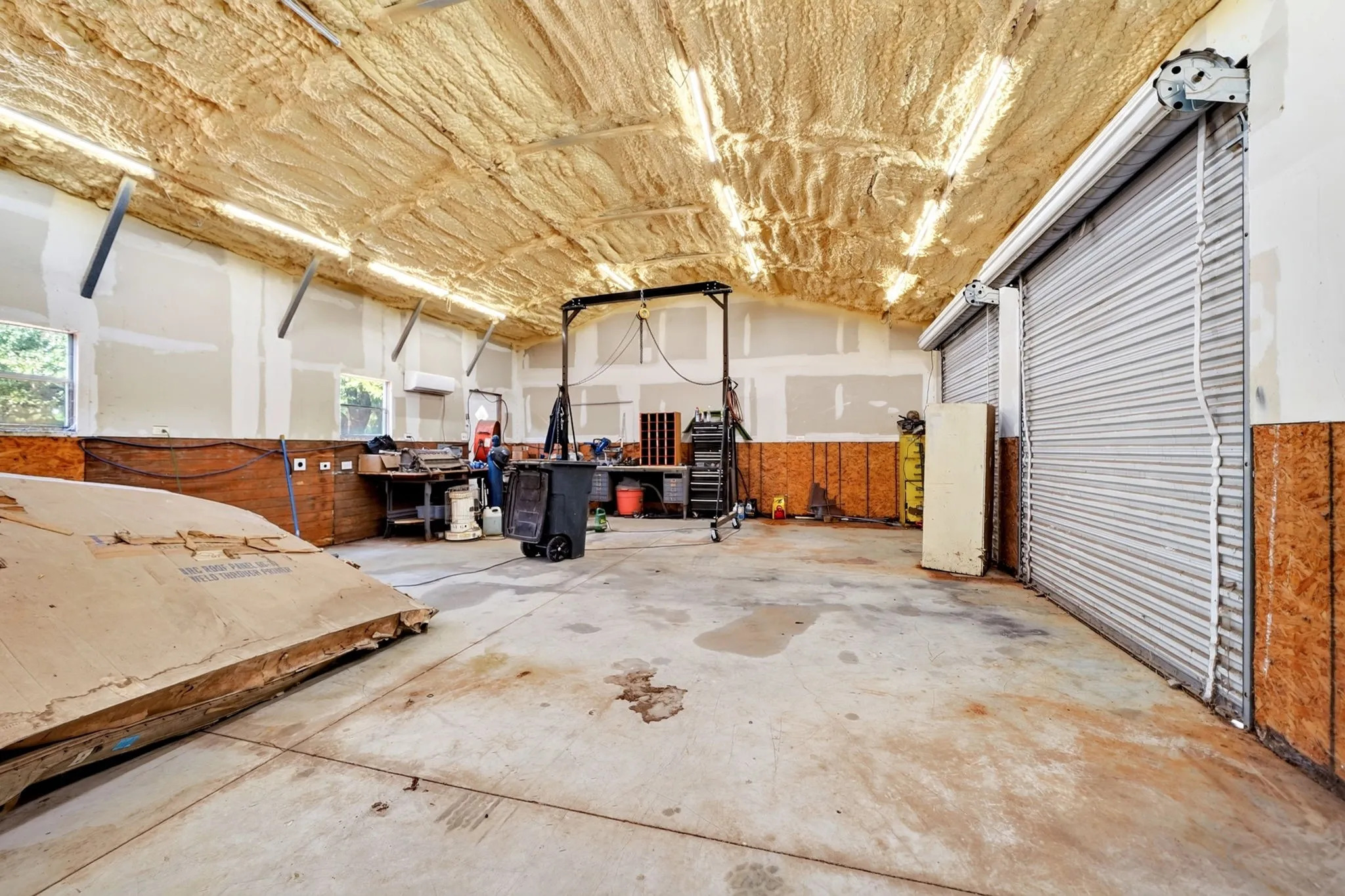 Expansive interior space featuring a concrete floor, insulated ceiling, multiple roll-up doors, and exposed wall framing