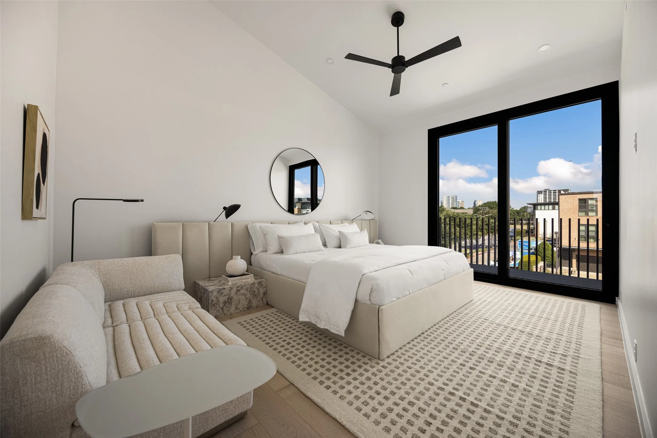 Vaulted ceiling, wood-finish flooring, floor-to-ceiling sliding glass doors, black ceiling fan, and black balcony railing
