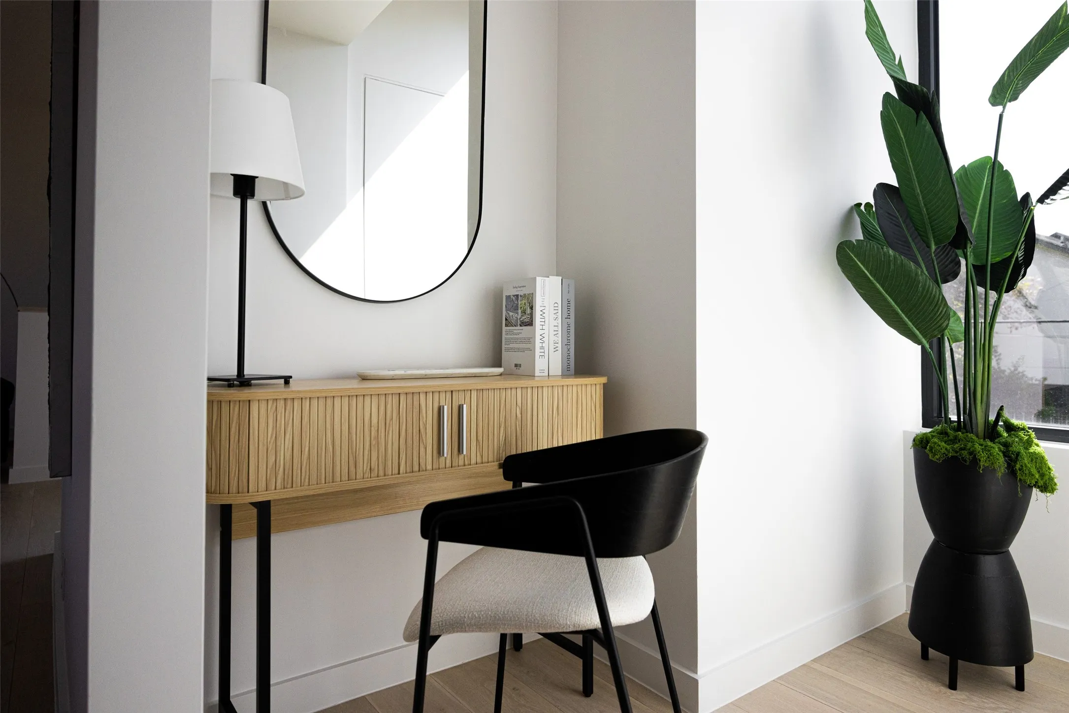 Light wood-finish flooring, half-round wall mirror, and a fluted wood console with metal legs