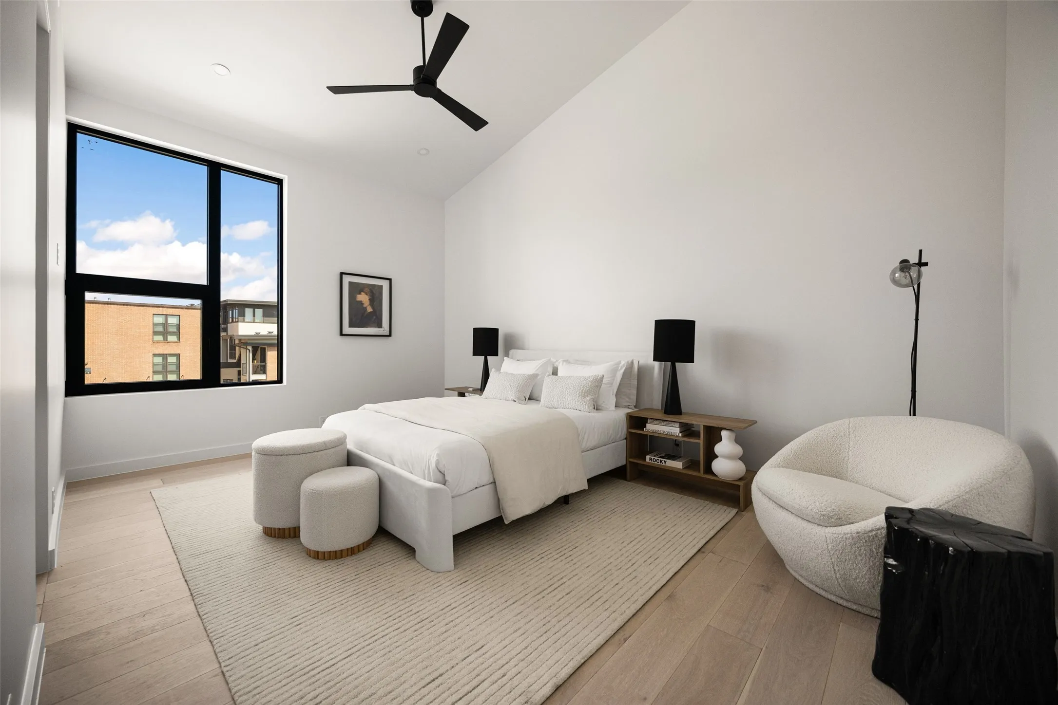 Vaulted ceiling with a black ceiling fan, large black-framed windows, and wood-finish flooring
