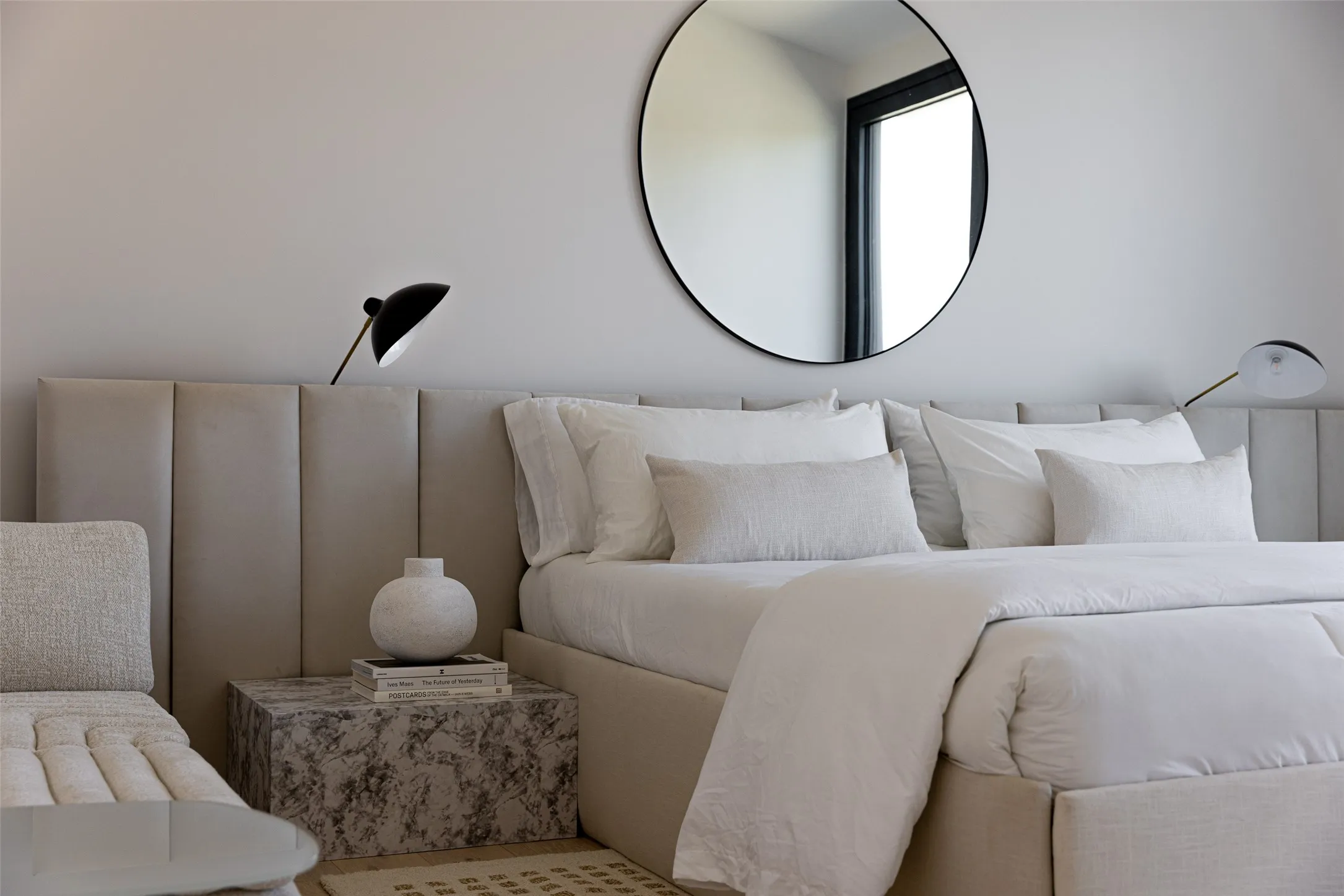 Wall-mounted lighting fixtures, an upholstered headboard, and a round wall mirror