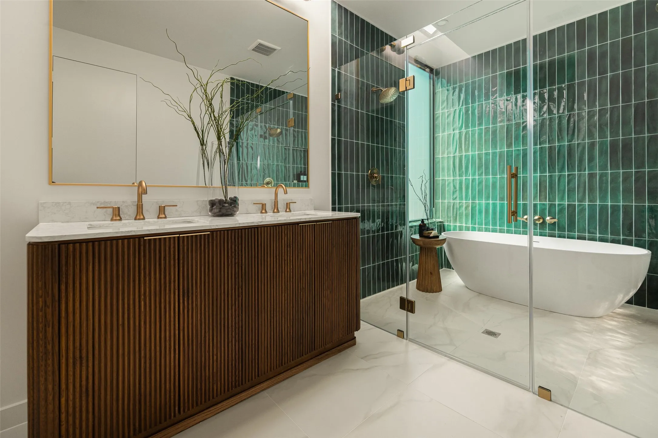 Dual vanity with white countertop, fluted wood-finish cabinetry, and gold-finish fixtures