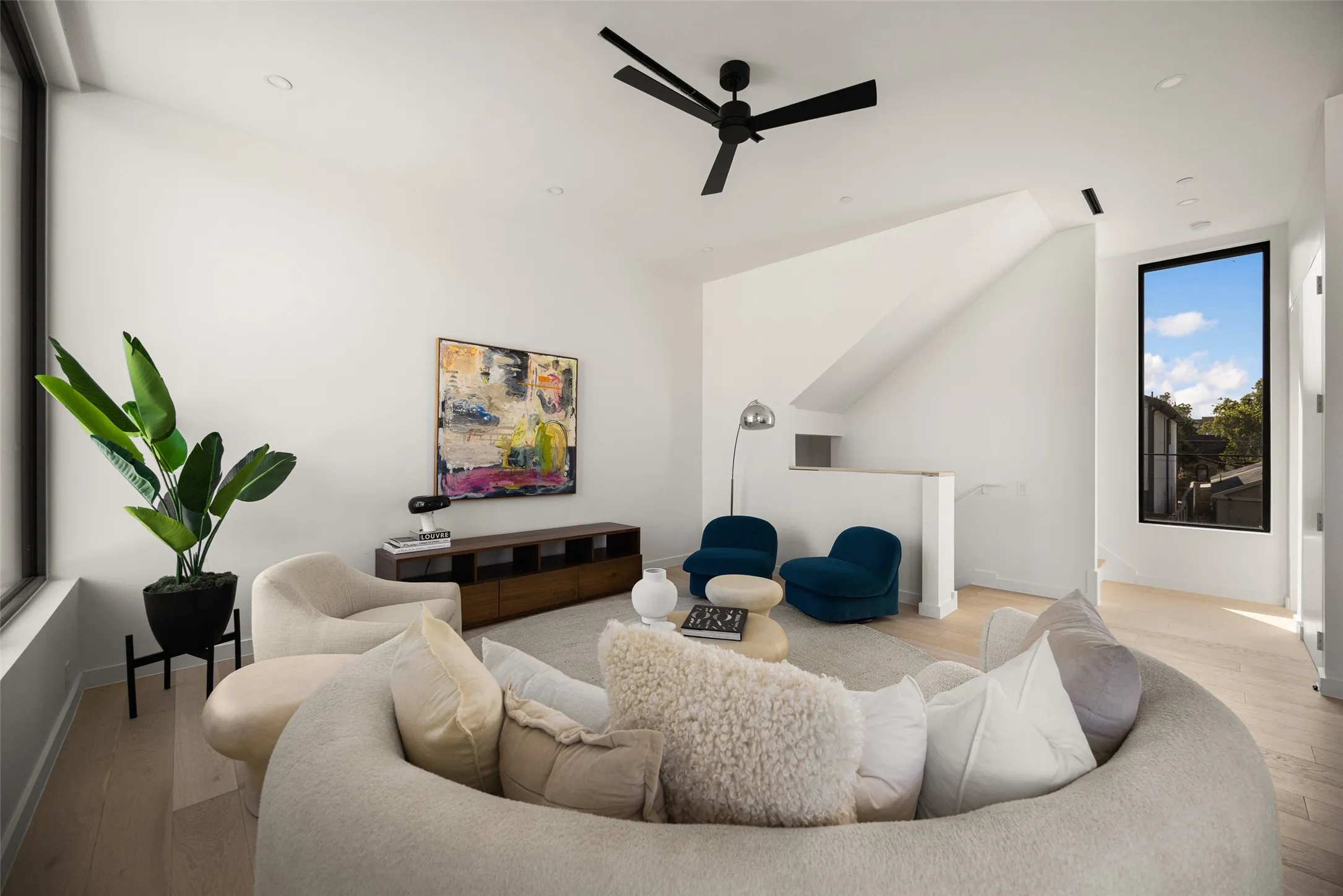 Spacious living area featuring high ceilings, wood-finish flooring, recessed lighting, and a contemporary ceiling fan