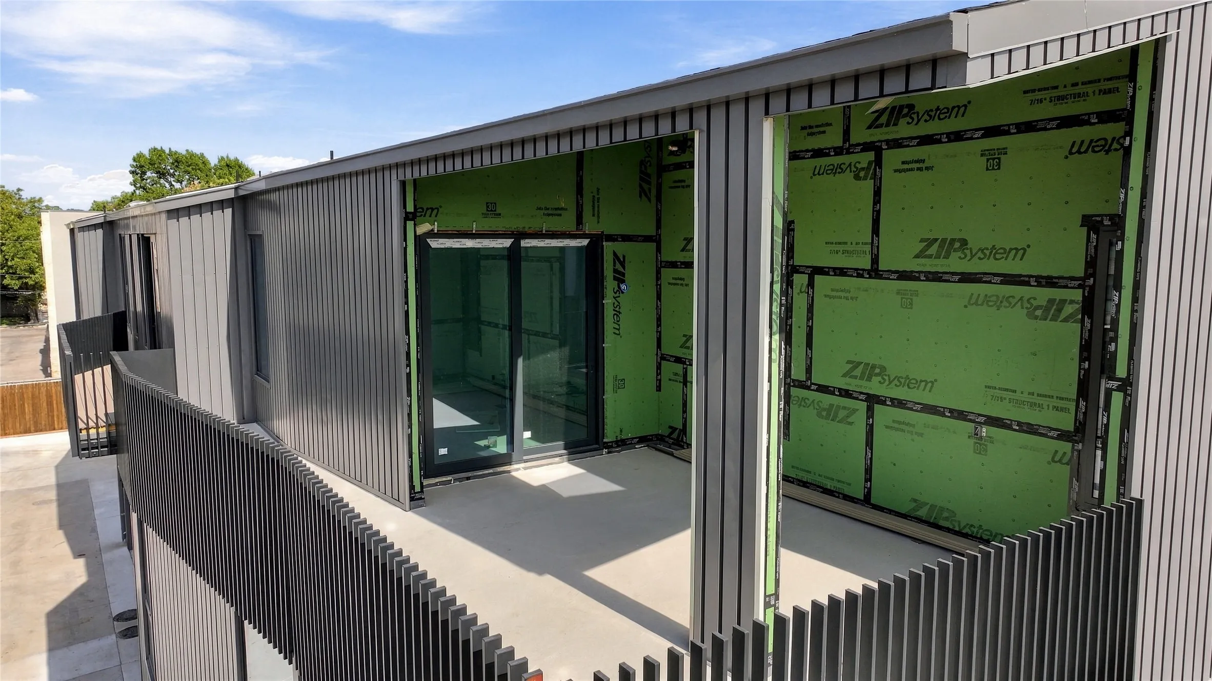 Exterior featuring vertical panel siding, multiple balconies with horizontal slatted railings, and large sliding glass doors