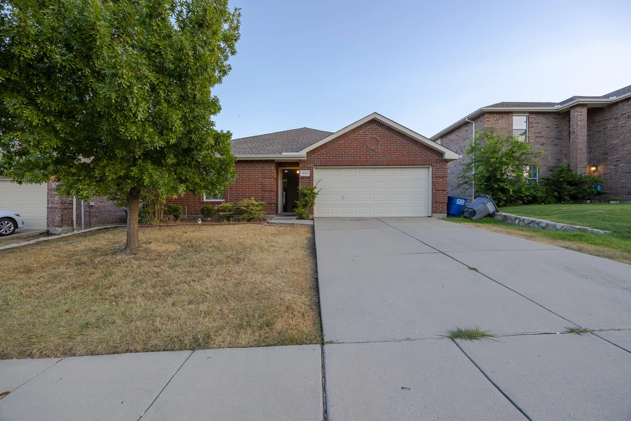 Brick exterior residence featuring an attached garage and a concrete driveway