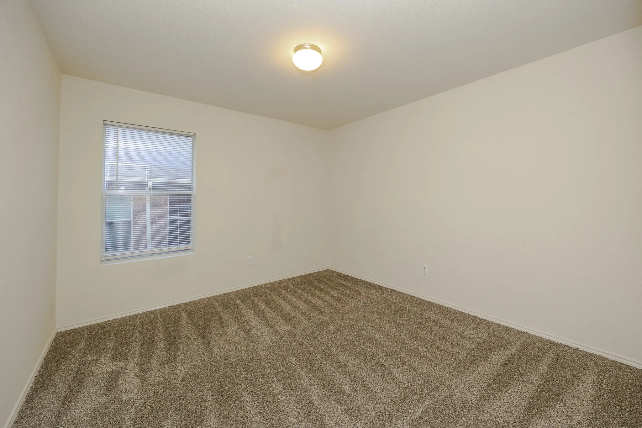 Wall-to-wall carpeting with geometric pattern, neutral-toned walls, and a ceiling-mounted light fixture