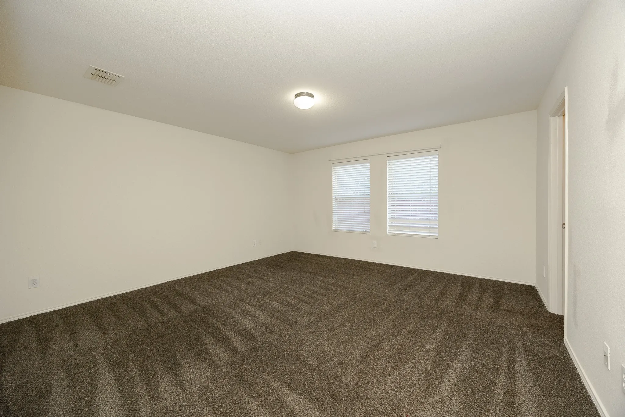 Neutral-toned walls complement the textured brown carpeting