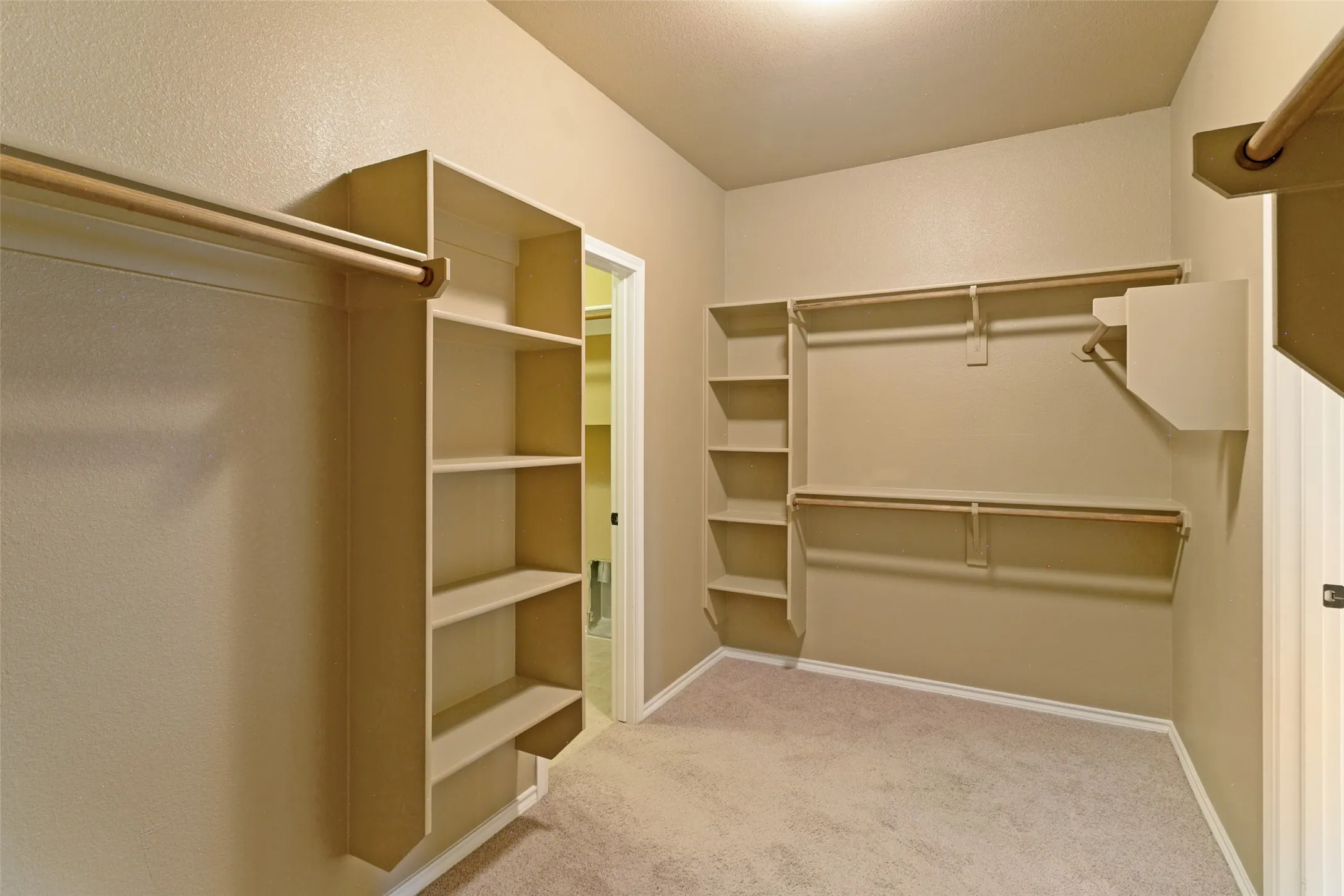 Walk in closet in primary bedroom. View of the laundry room from the walk in closet