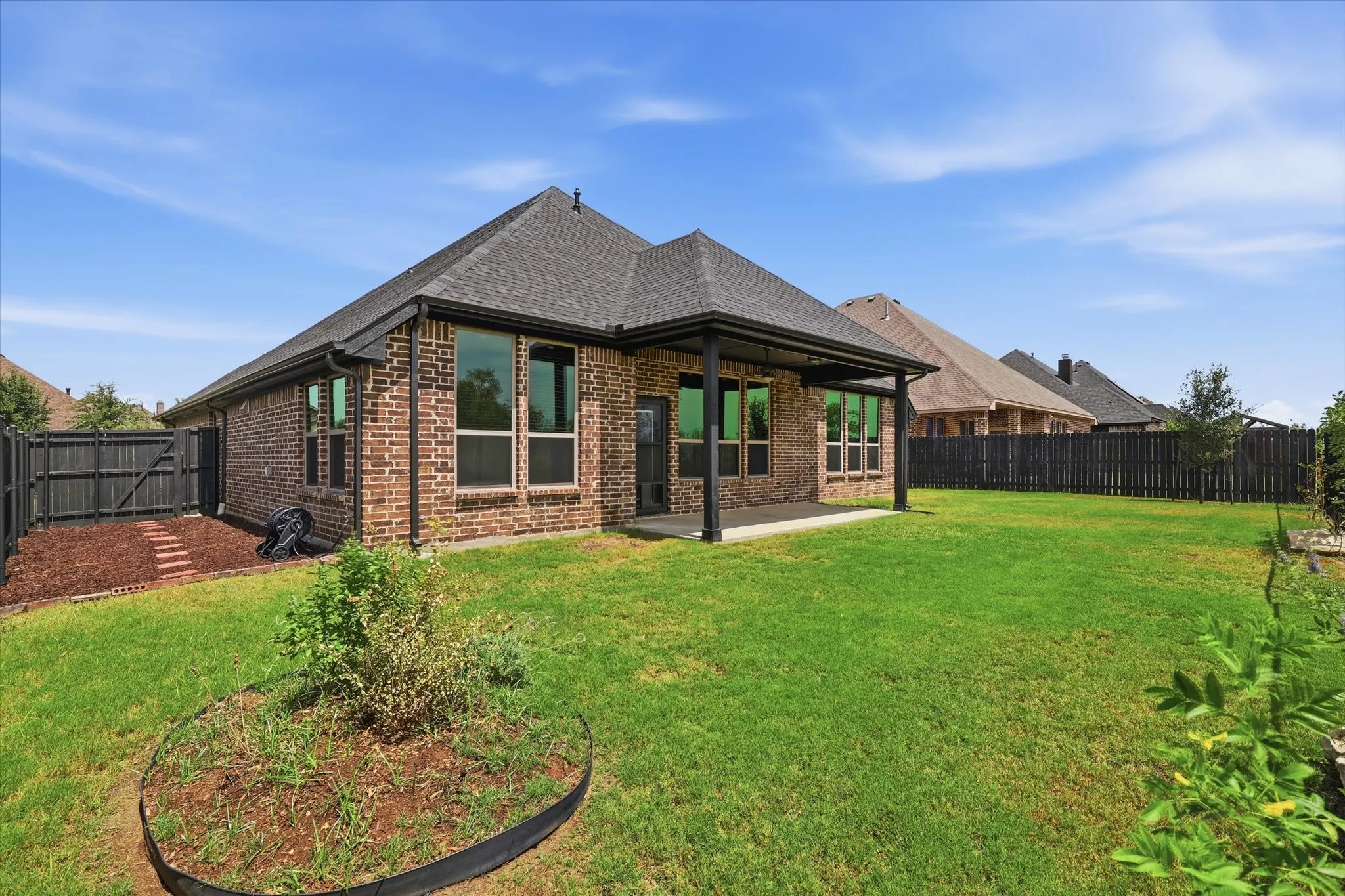 Combination of wood privacy fencing along the sides and wrought-iron fencing across the rear preserves the open view beyond the property and keeps the yard from feeling closed in.