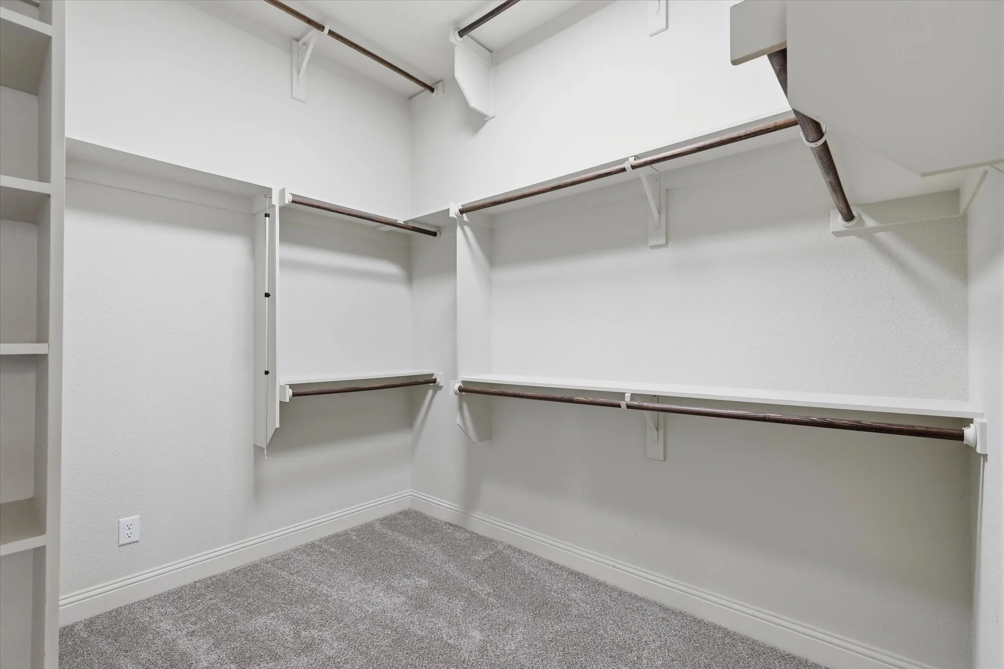 Large primary bedroom walk-in closet with extensive hanging space, multiple levels of rods and shelving, plus built-in open shelving.