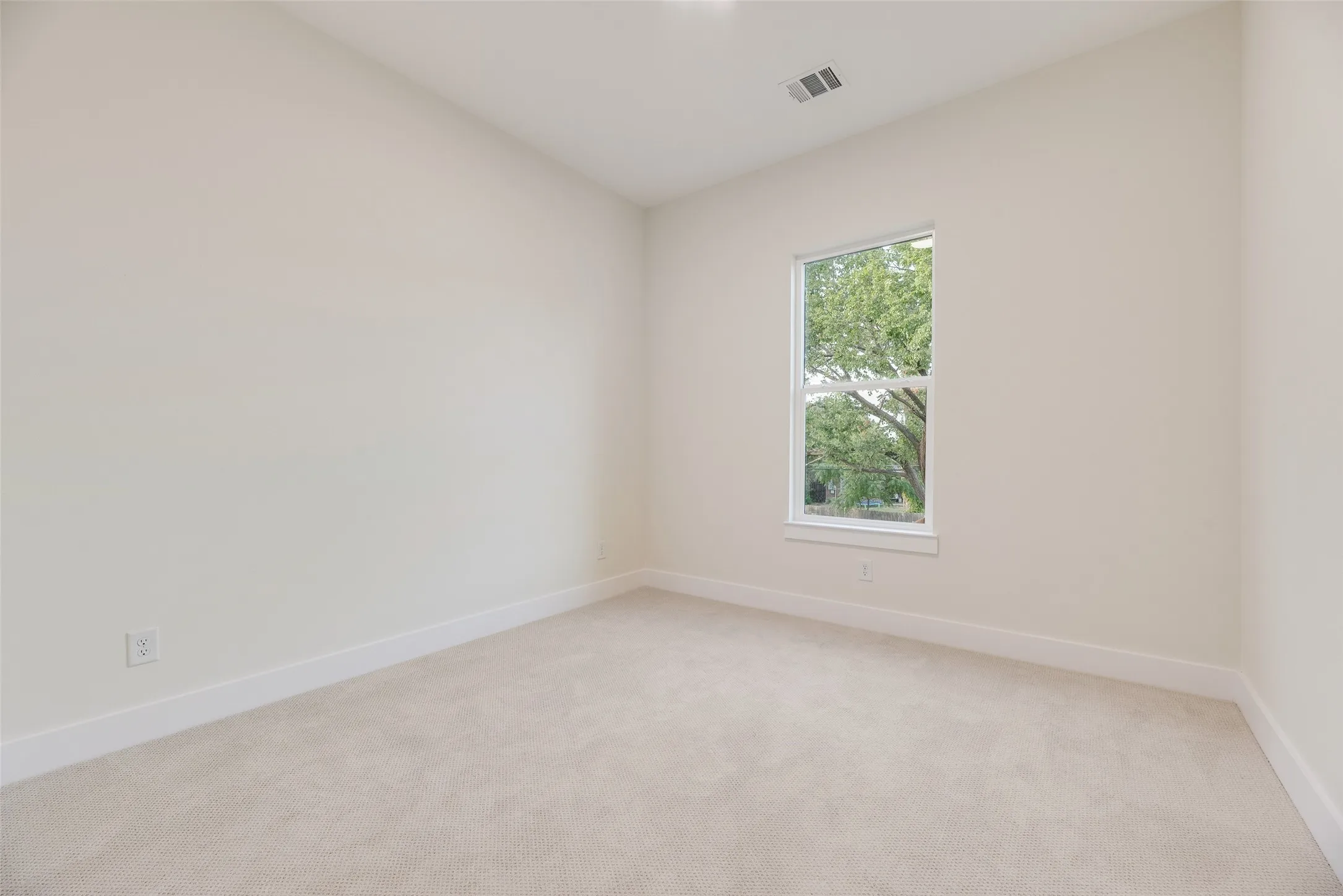 Neutral wall paint, light-colored carpet, single window with white trim, white baseboards, and ceiling-mounted register