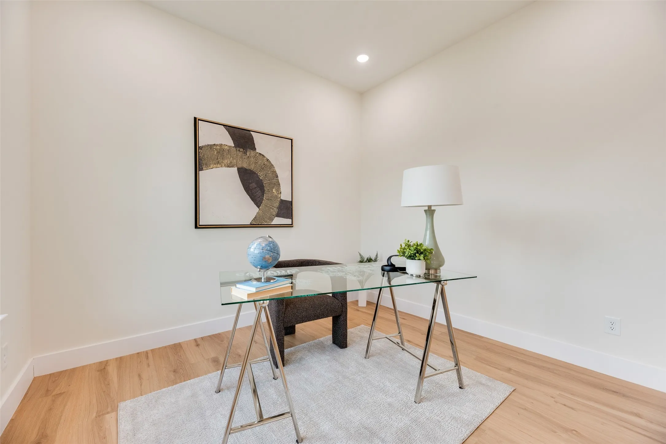 Recessed ceiling light, light-toned wood-finish flooring, and crisp white walls