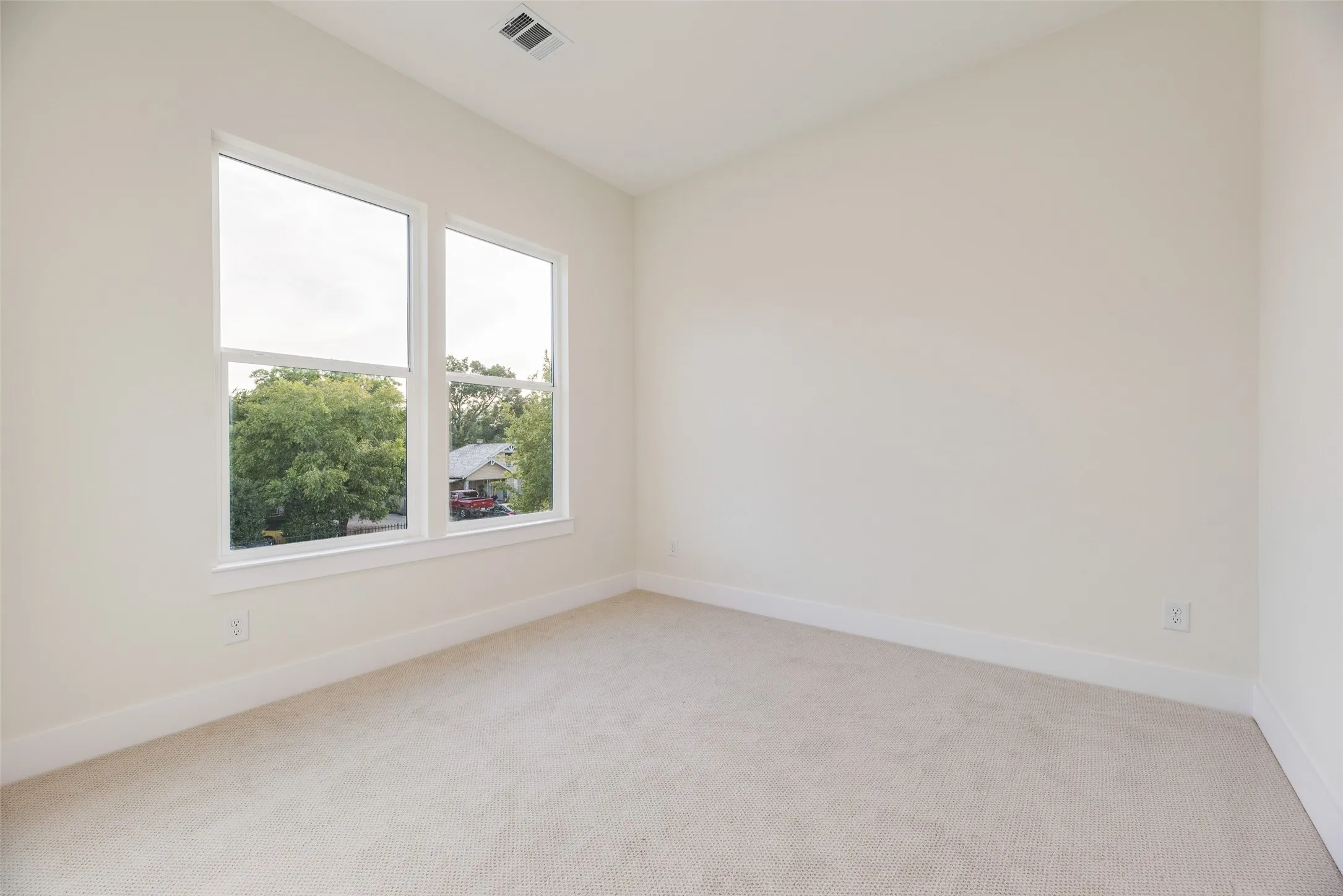 Recessed ceiling vent, neutral carpet, white trim, and a dual-pane window