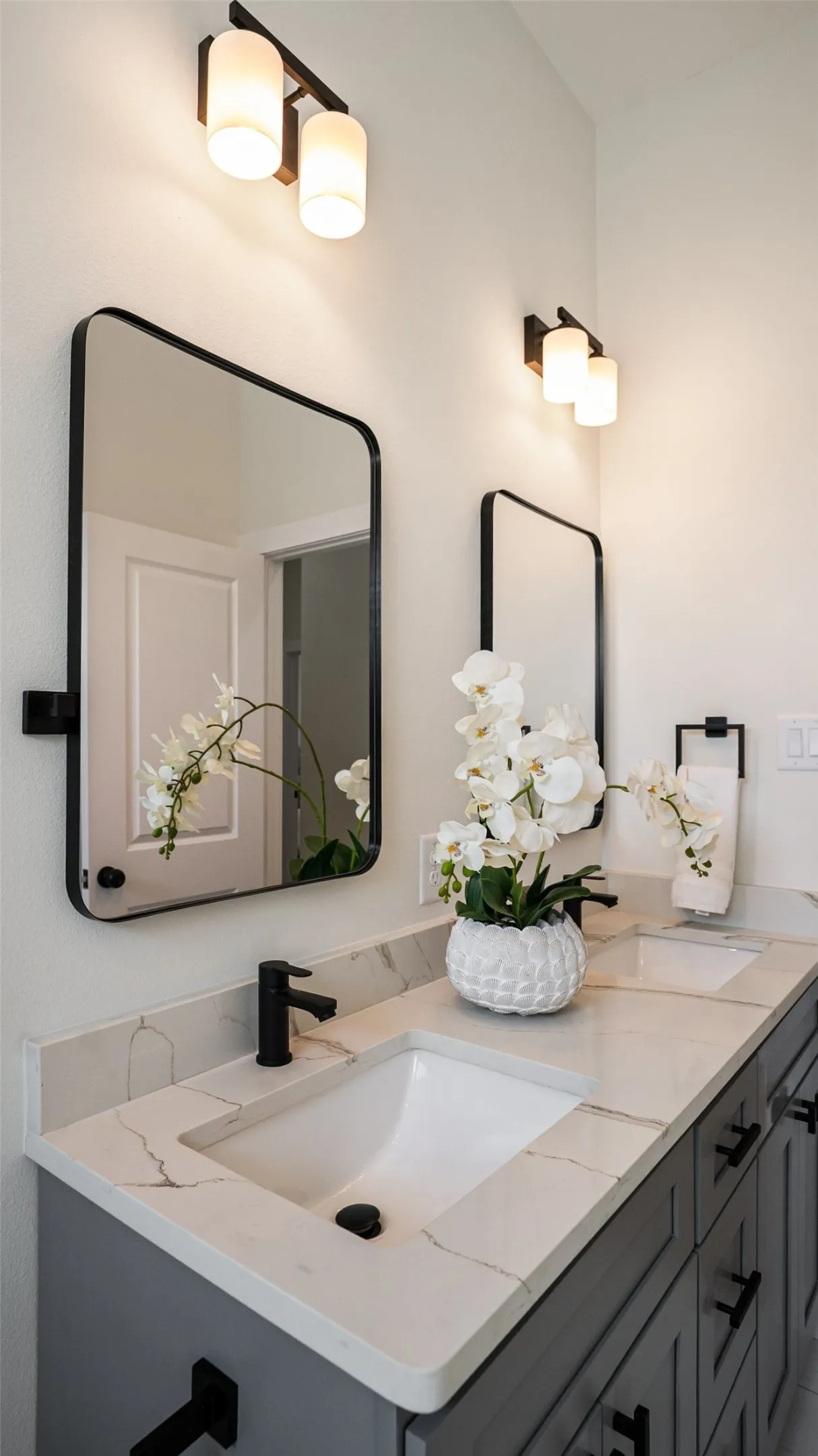 Dual vanity with undermount sinks, stone-finish countertops, and matte black fixtures
