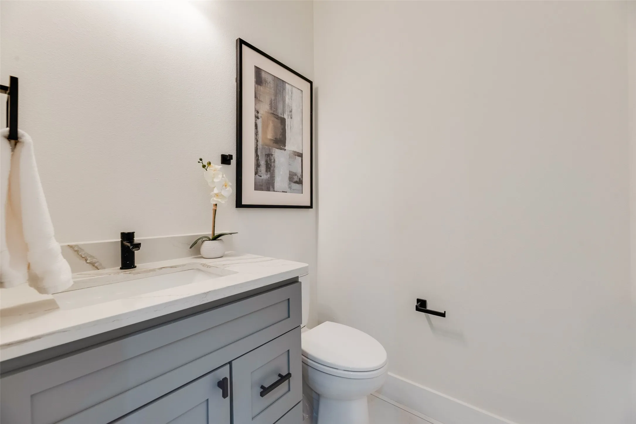 Built-in vanity with gray cabinetry, white countertop, integrated sink, and black fixtures
